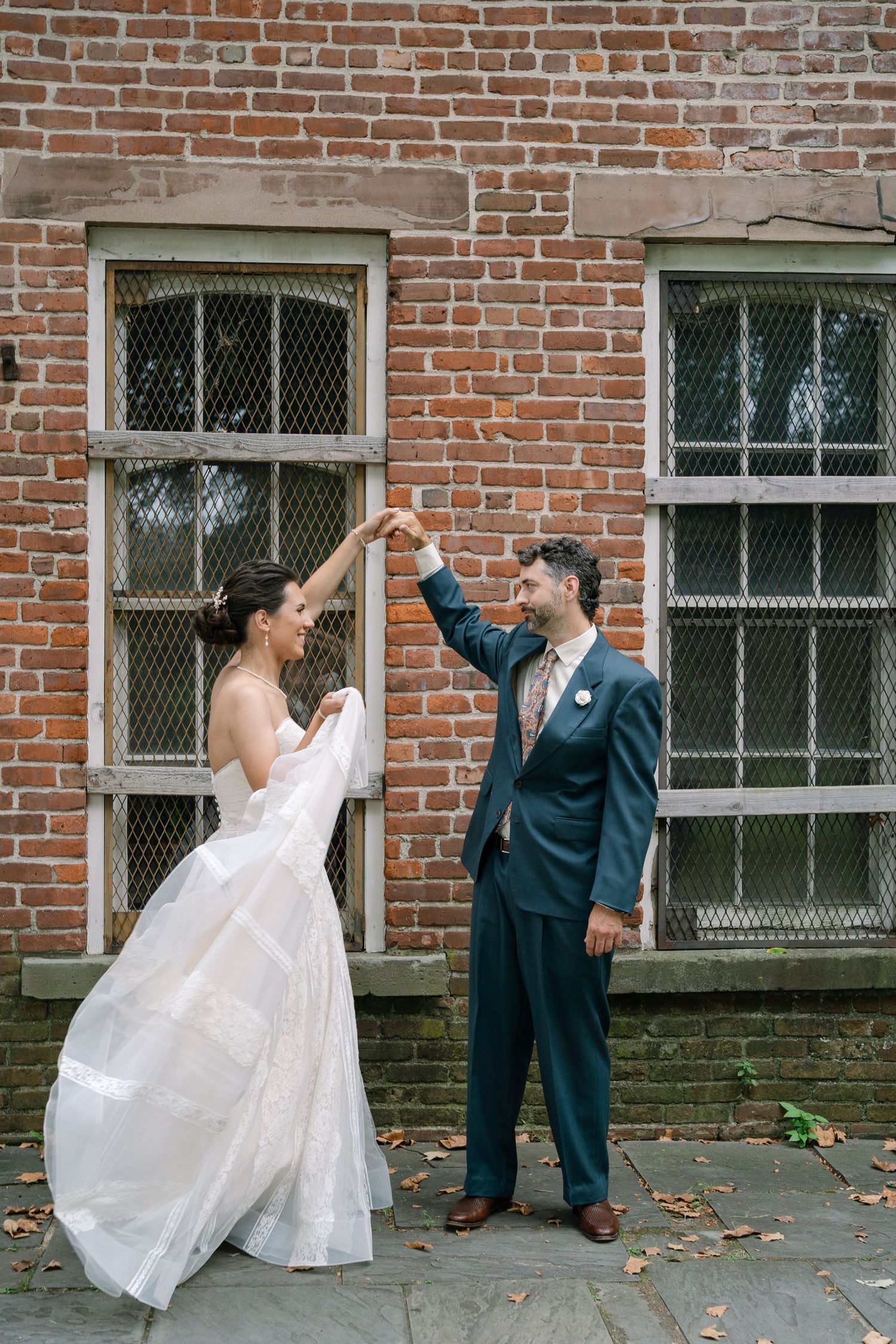 A sequence of playful wedding photos taken against a red brick wall with windows.