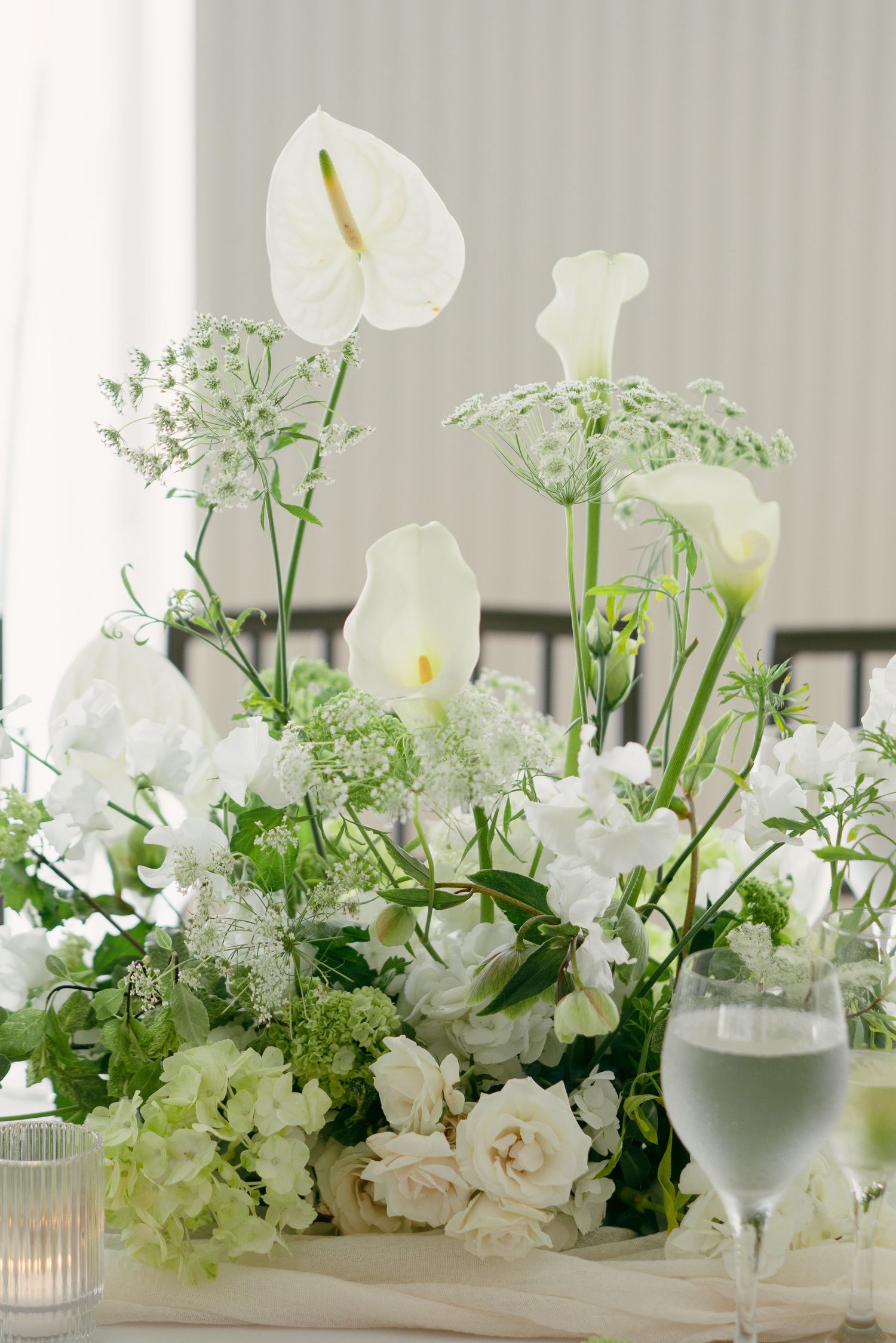 Elegant white floral centerpieces with orchids and delicate greenery arranged on a table for a wedding reception.