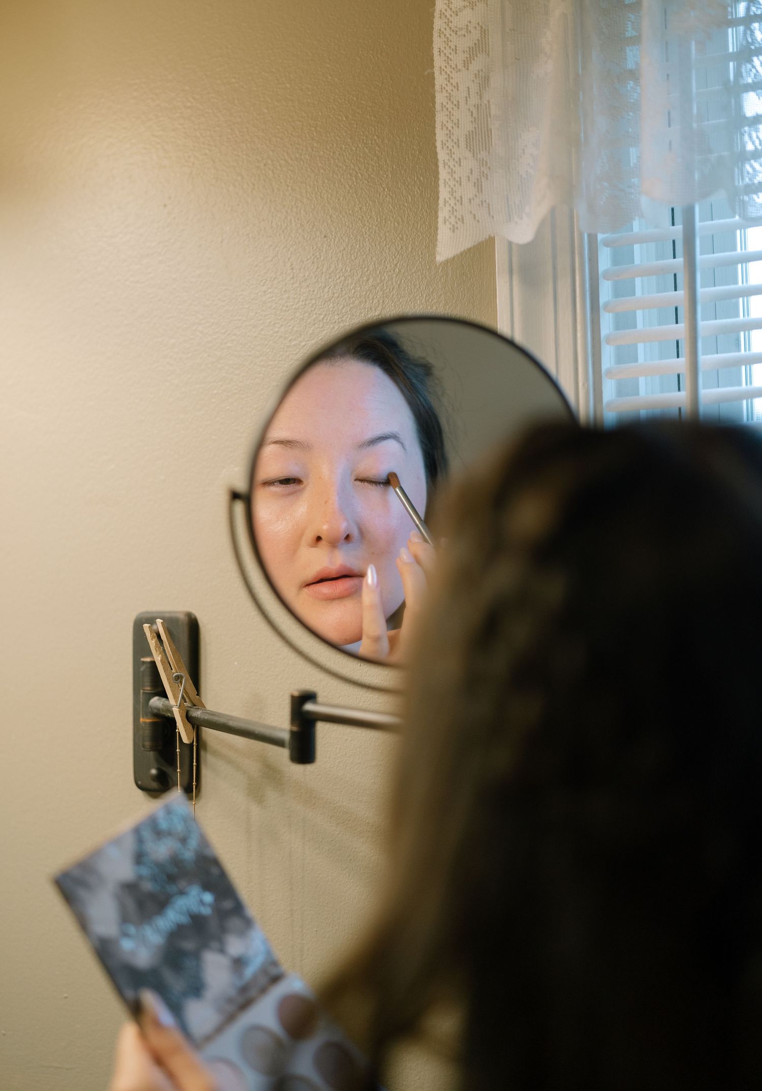 A close-up reflection in a magnifying mirror shows preparation details during a wedding day.
