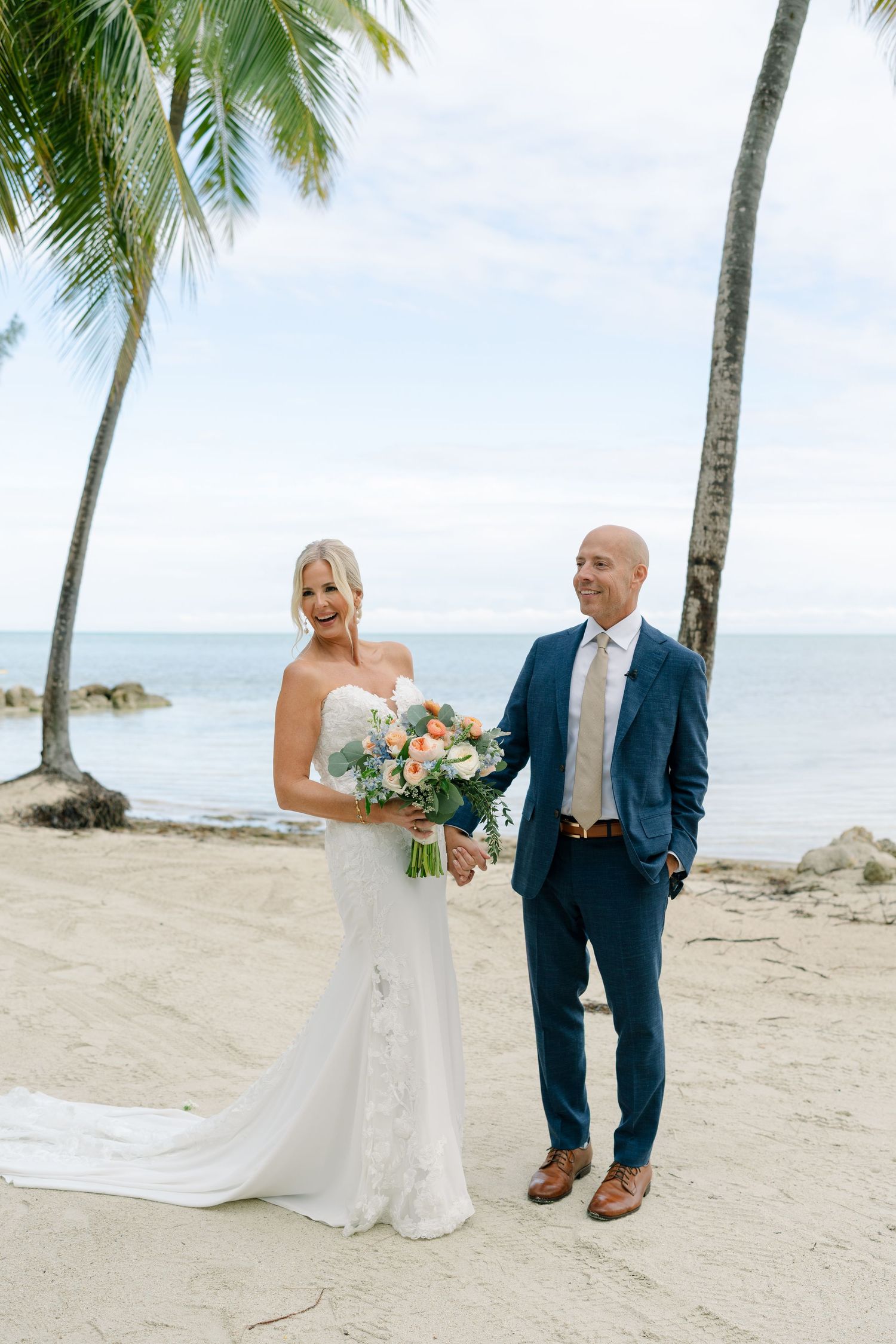 A romantic beach wedding ceremony with palm trees and ocean backdrop in a tropical destination.