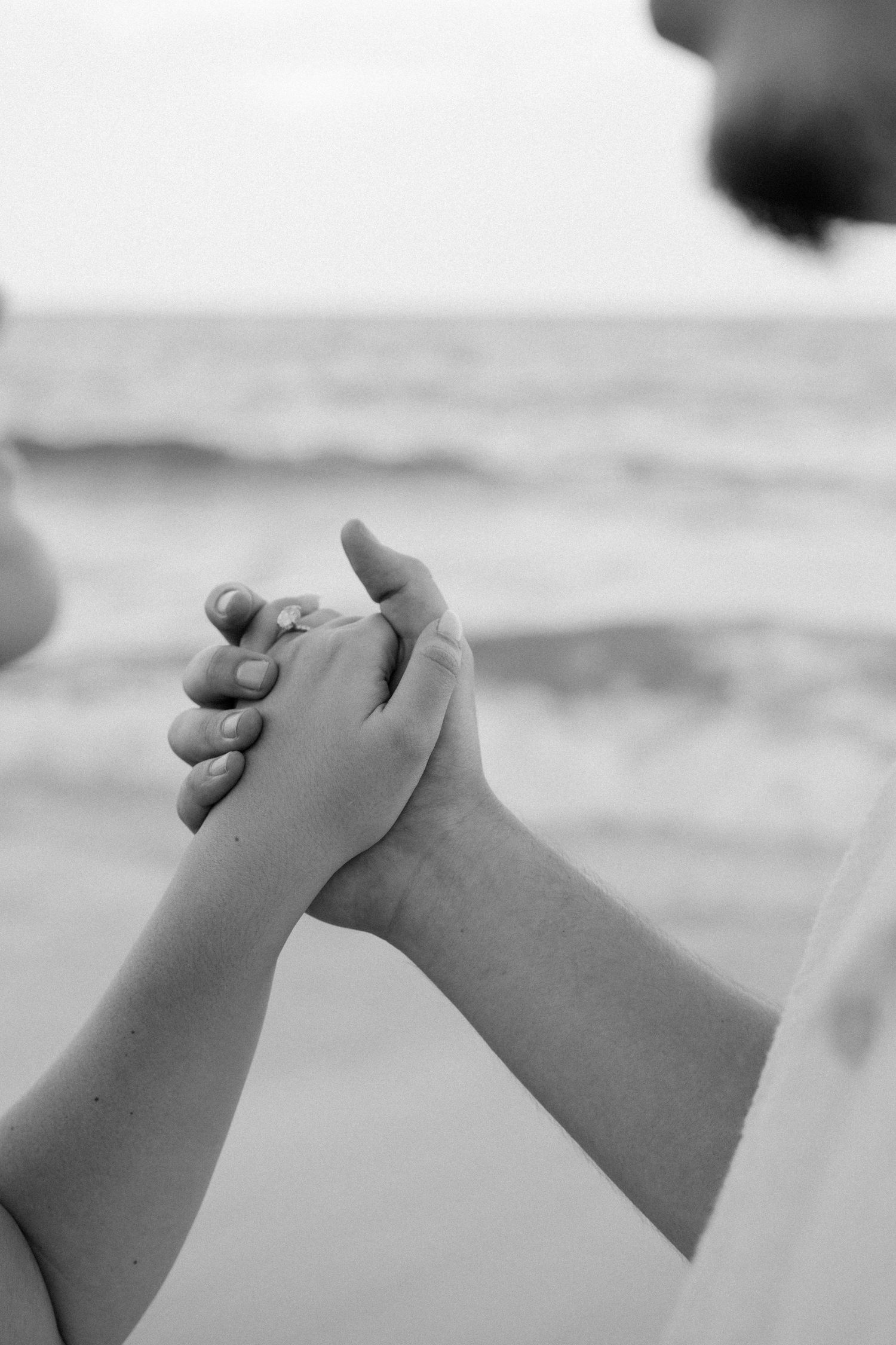 A series of black and white photographs showing clasped hands in a repeating pattern against a light background.