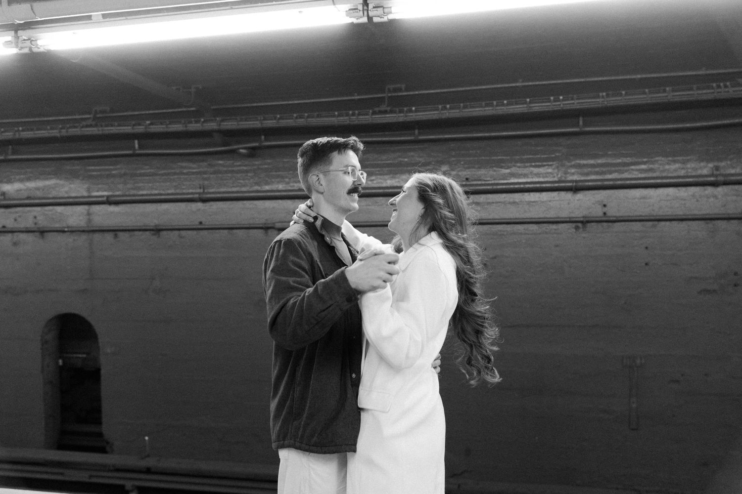 A black and white photo sequence shows a person dancing gracefully against an industrial background.