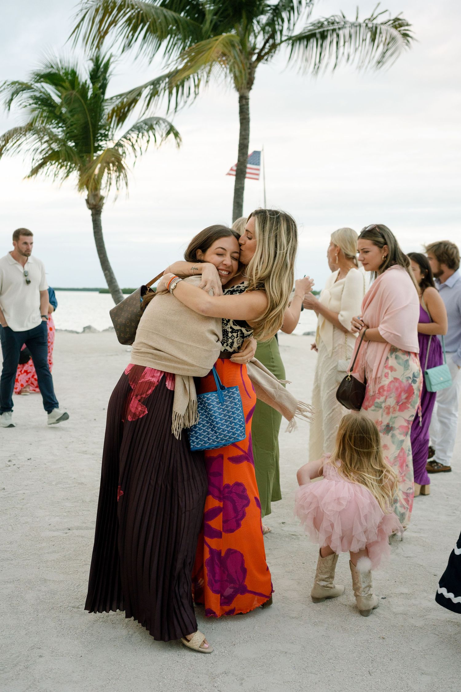 Beachside celebration with palm trees and people gathering on white sand.