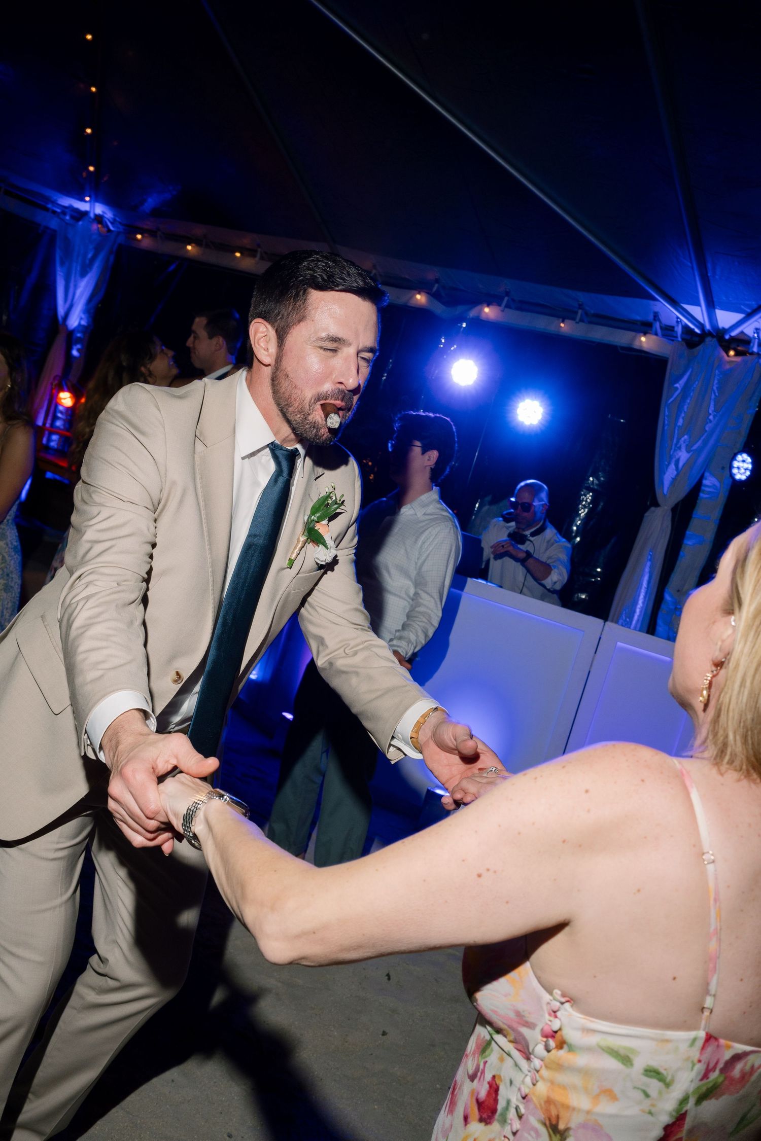 Energetic dancing and celebration at a wedding reception with blue lighting and party atmosphere.