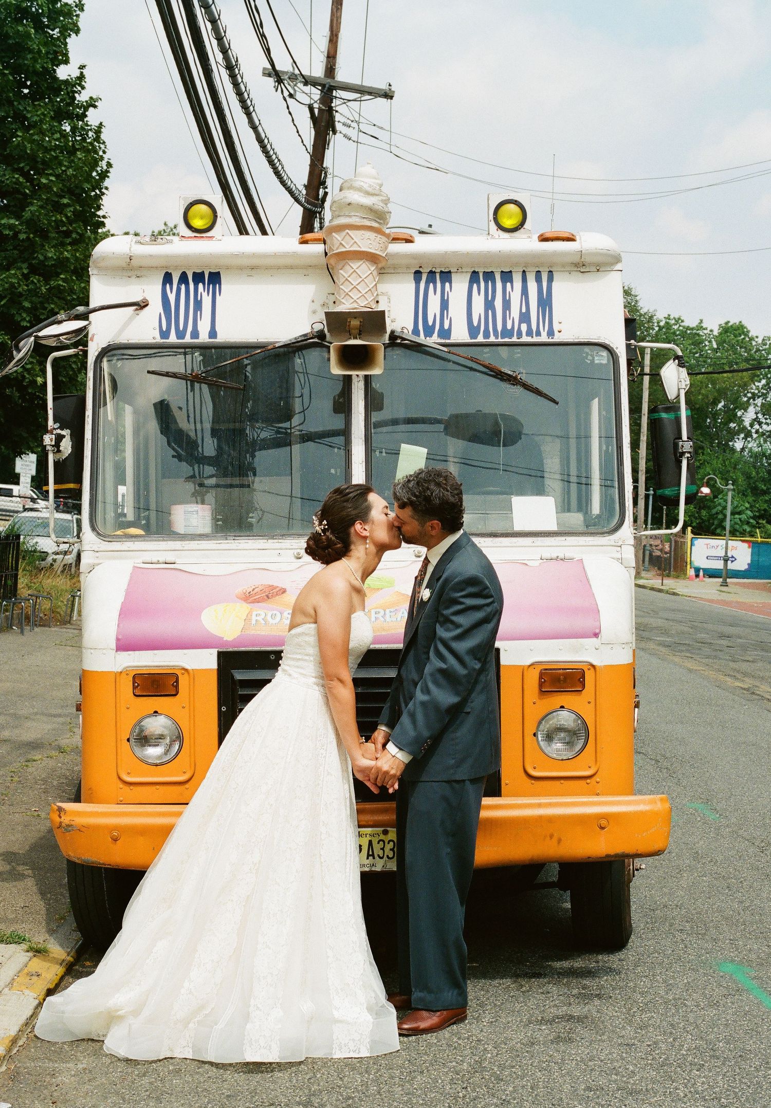A couple sharing a romantic moment in front of a vintage soft serve ice cream truck.