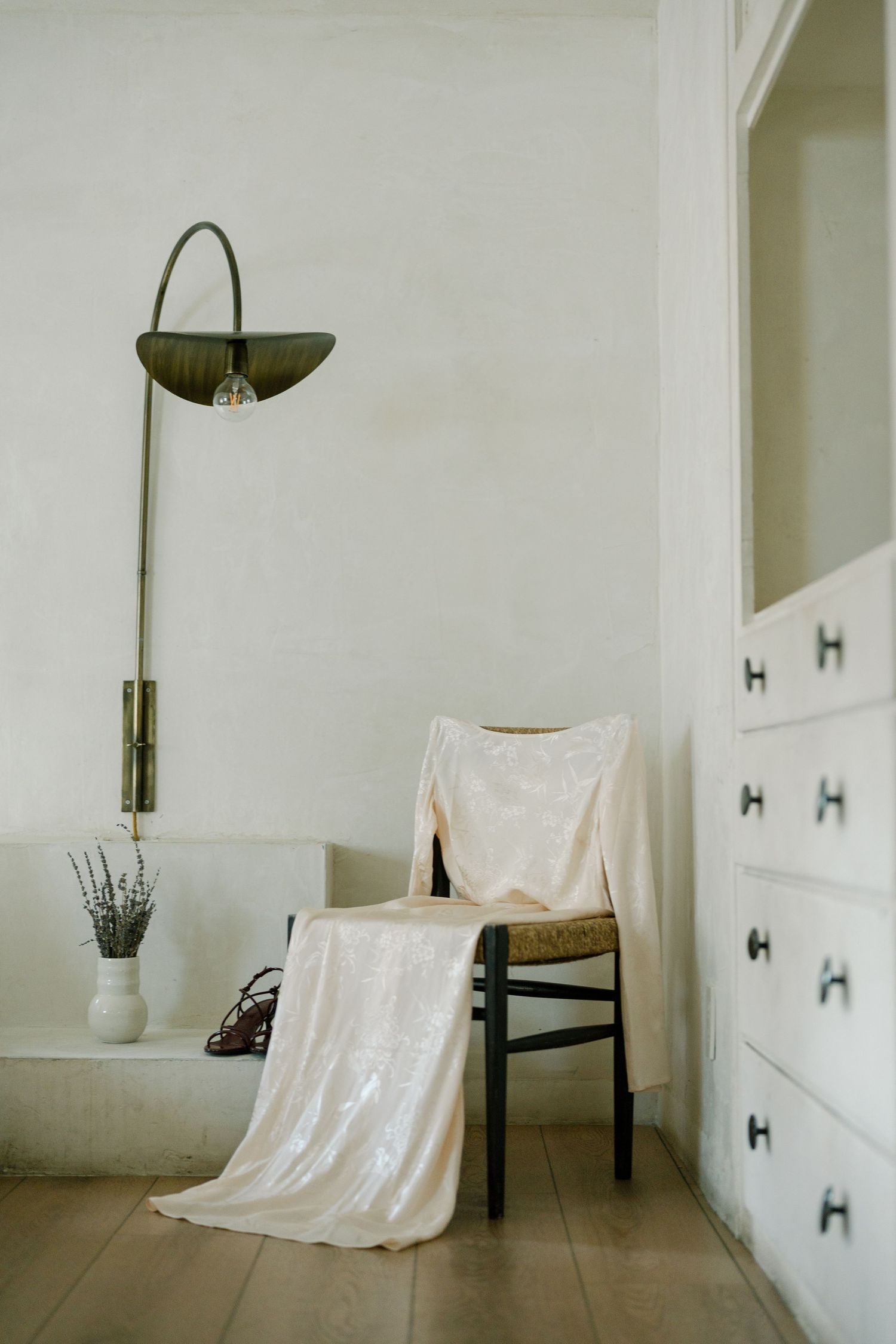 White fabric draped over furniture in a minimalist room with arched details and natural lighting.