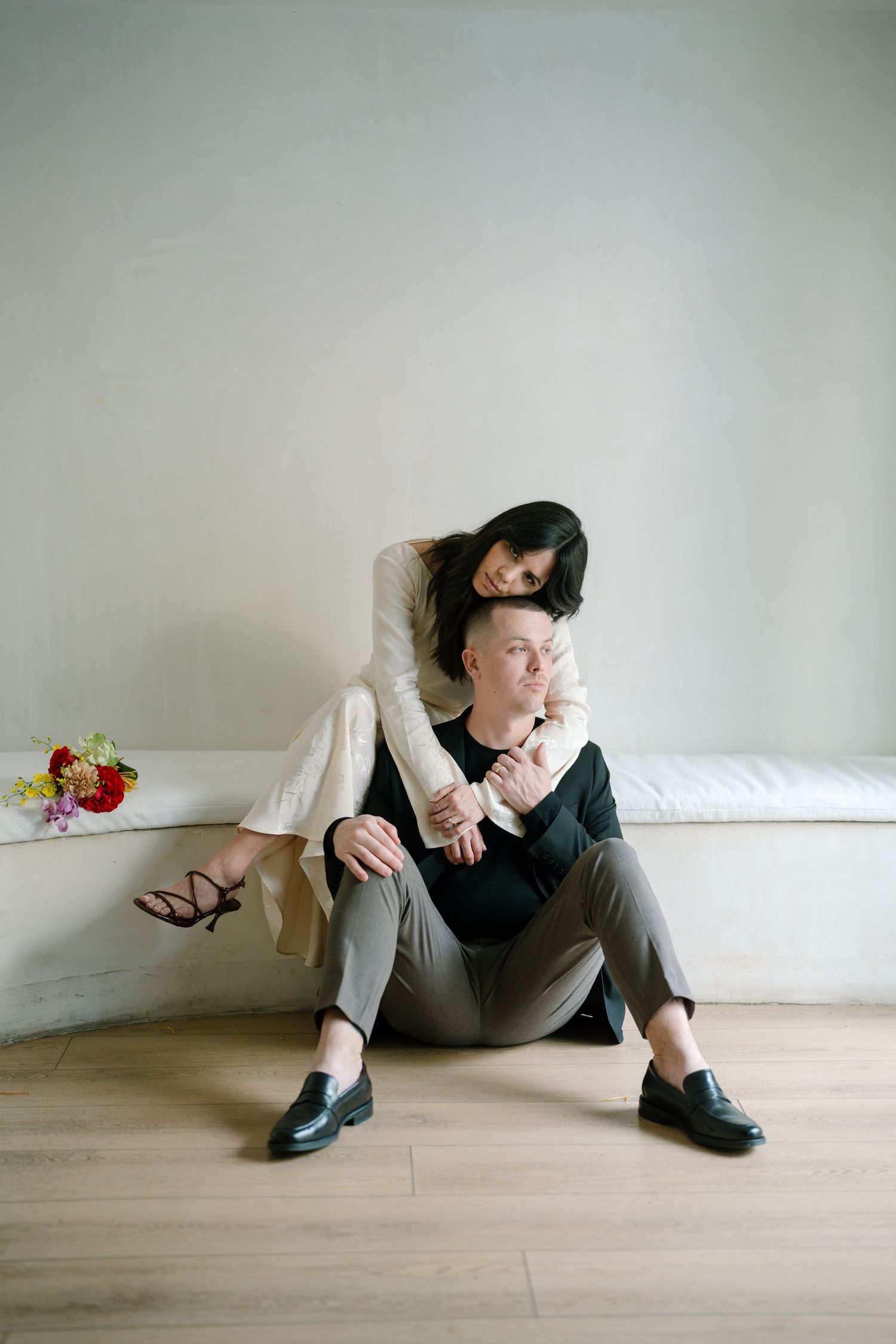 Minimalist photo series of couple in casual attire sitting on wooden floor.