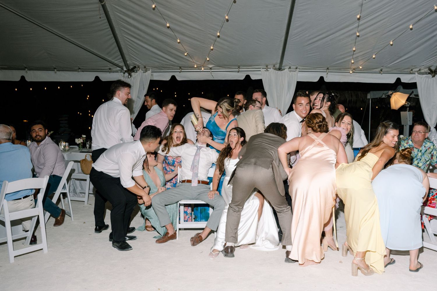 A large group of people are gathered at a festive outdoor event, some dancing and celebrating.