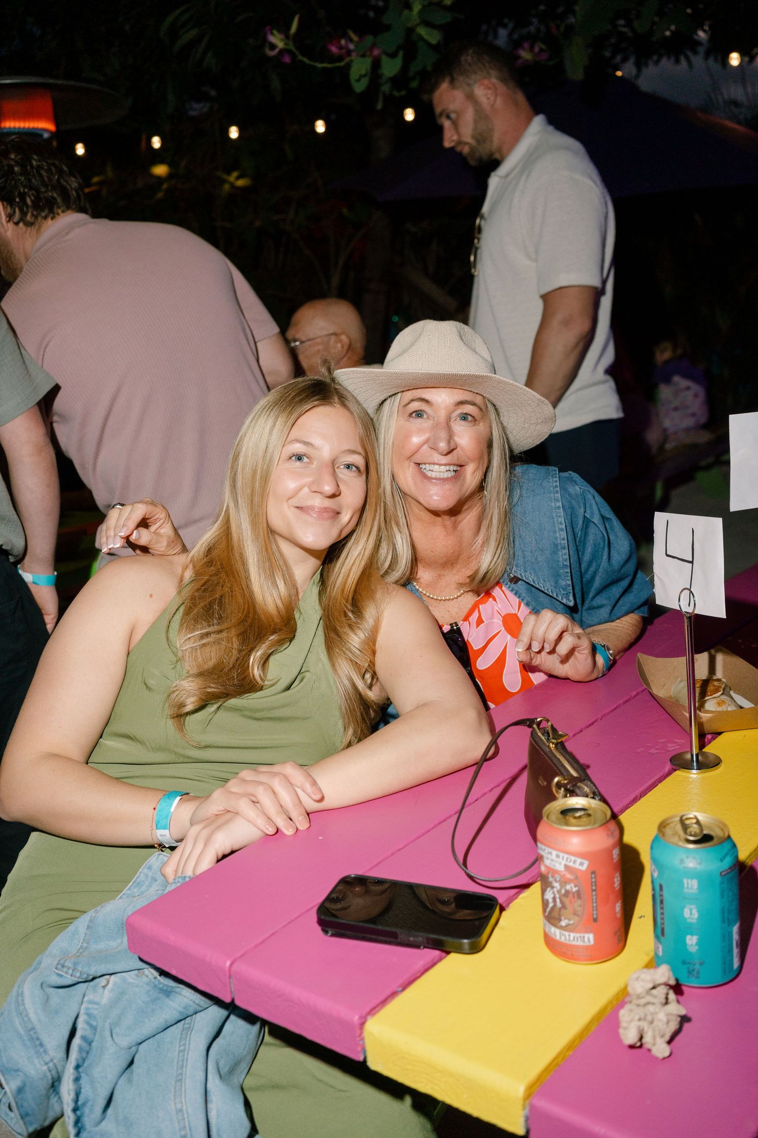 Friends enjoying a casual night out together at a colorful table with drinks and laughter.
