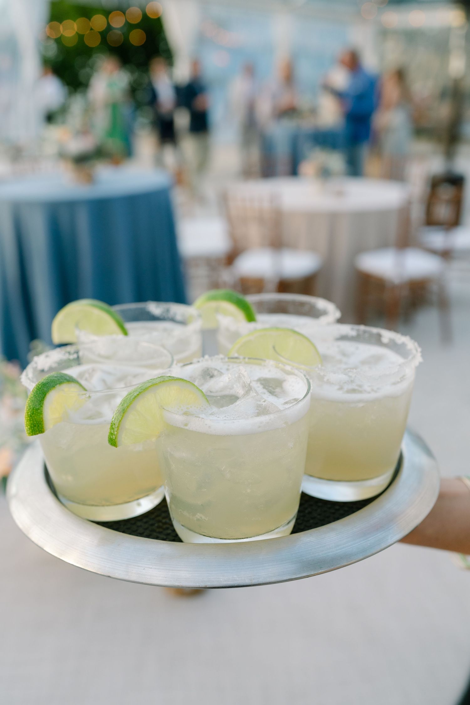 Fresh margarita cocktails garnished with lime slices served on a white plate at an elegant event.