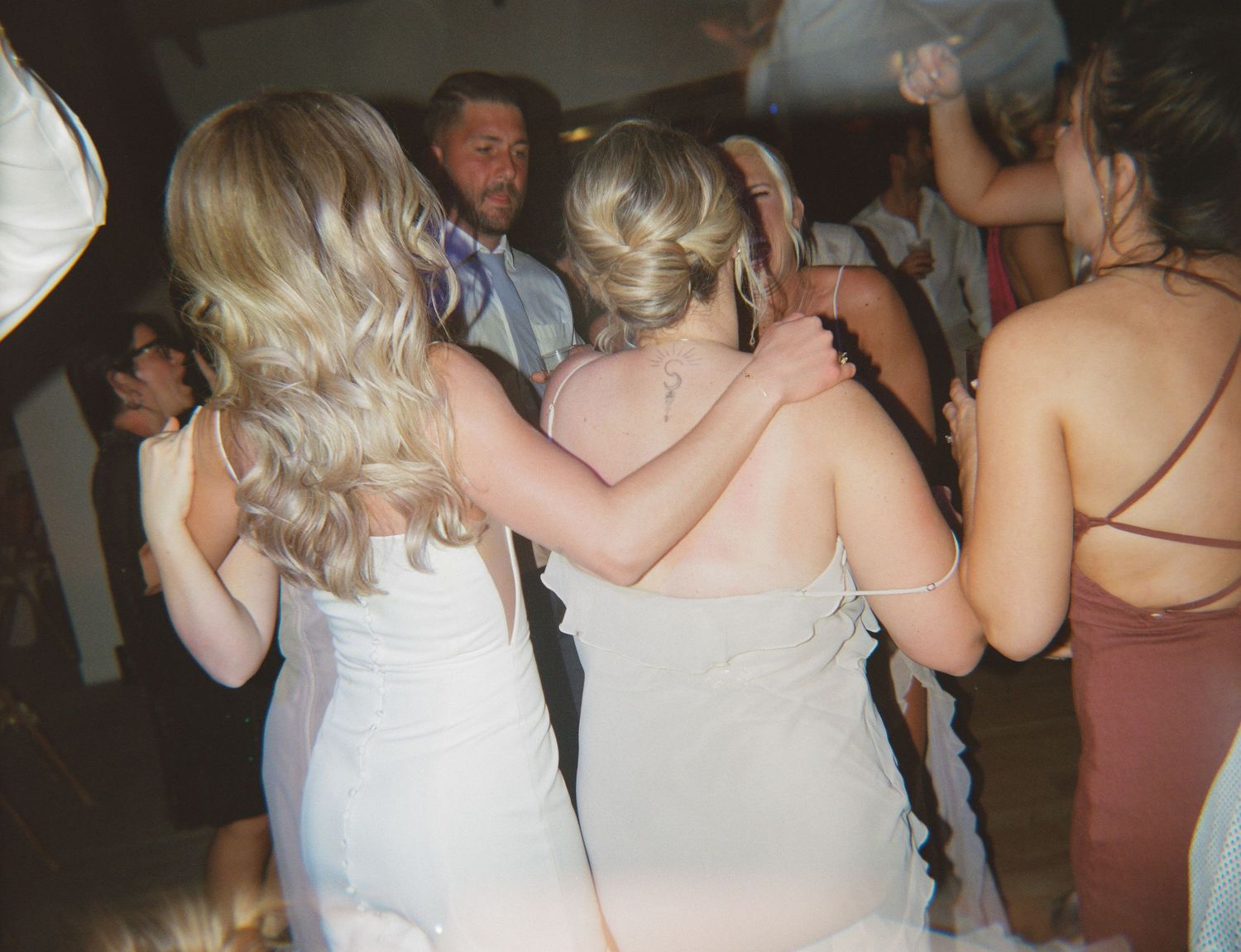 Group of people dancing and celebrating at a wedding reception in formal attire.