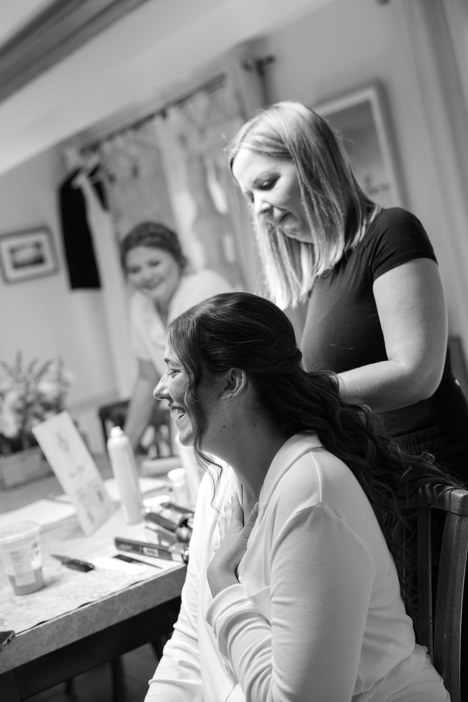 A woman is styling the hair of another woman in a salon setting.