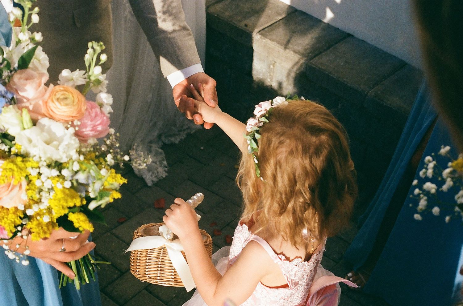 Wedding party members gathered around floral arrangements and decorative baskets in a bright setting.