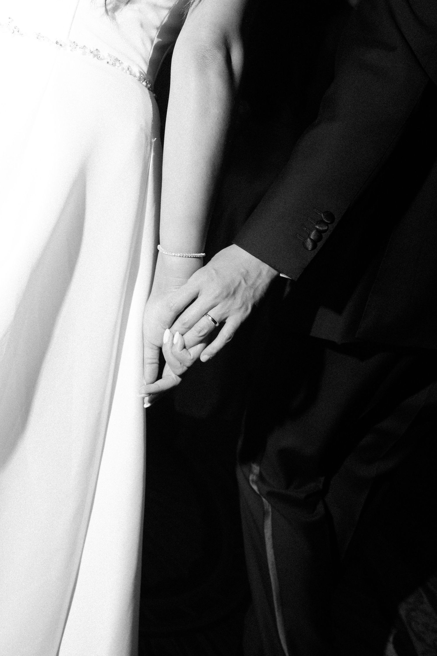 Close-up black and white details of wedding attire showing dress fabric and formal wear.