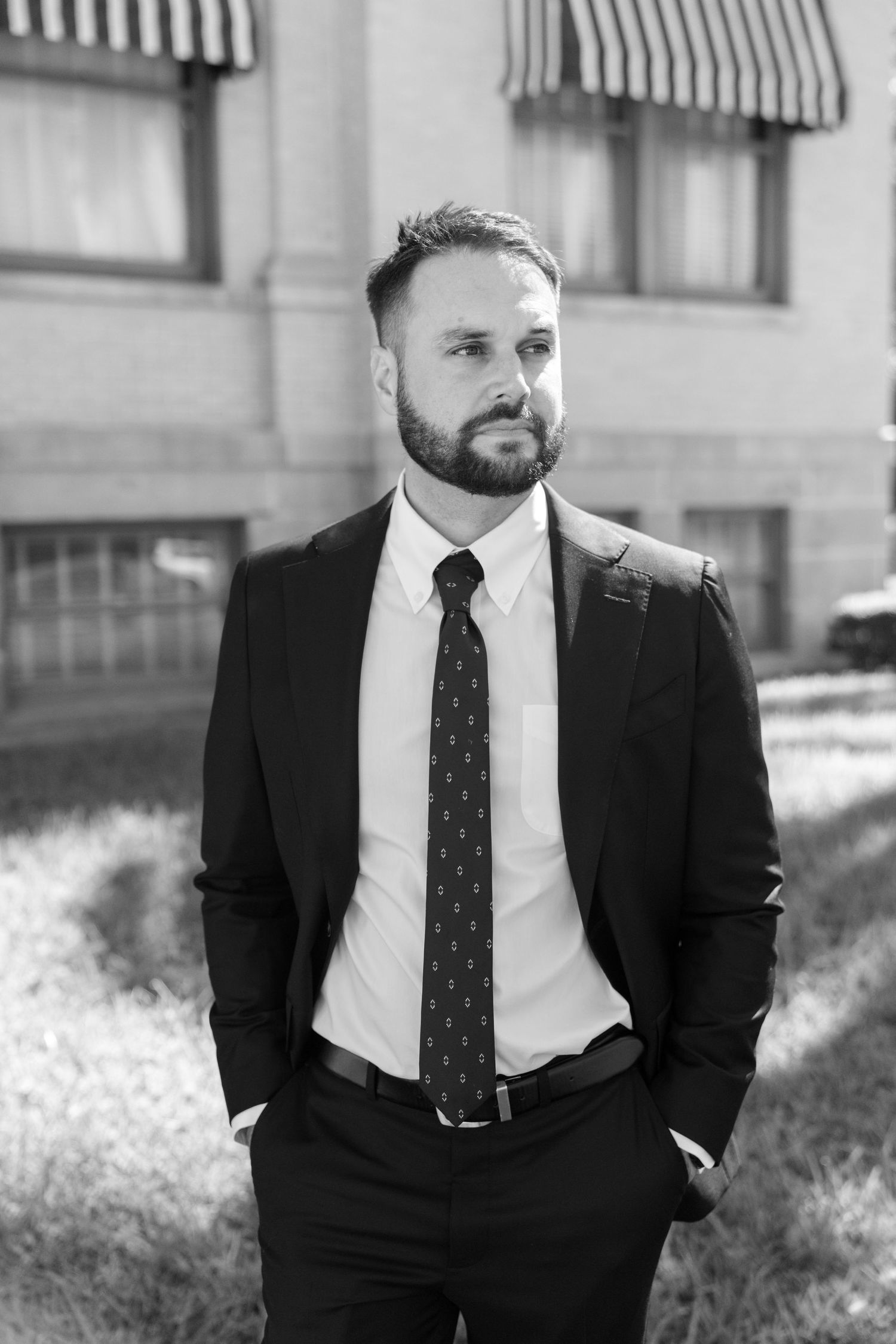 Professional portrait series showing a man in a black suit and tie against a building exterior.