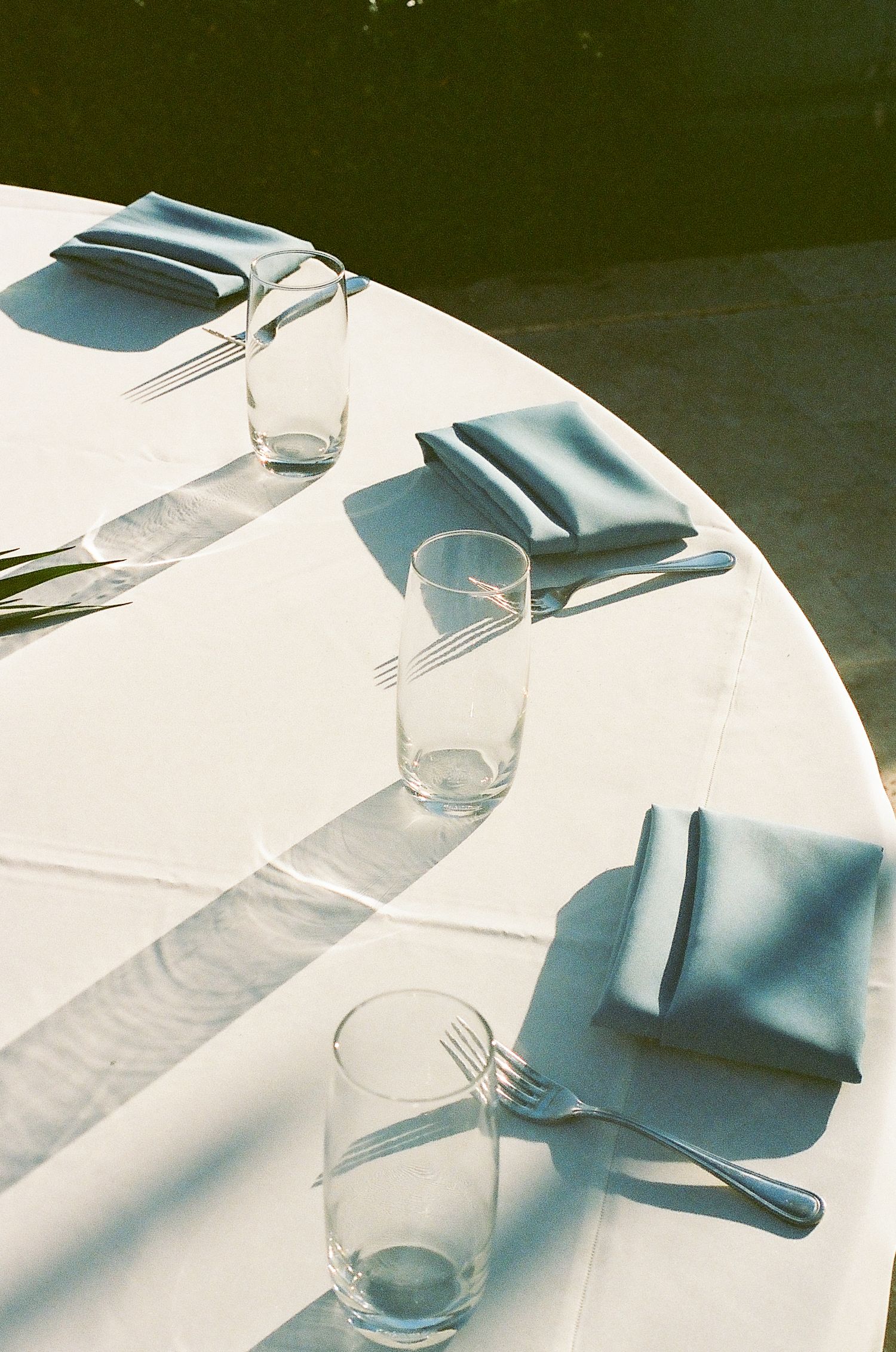 White tablecloths and place settings with blue napkins on round tables in a banquet hall.