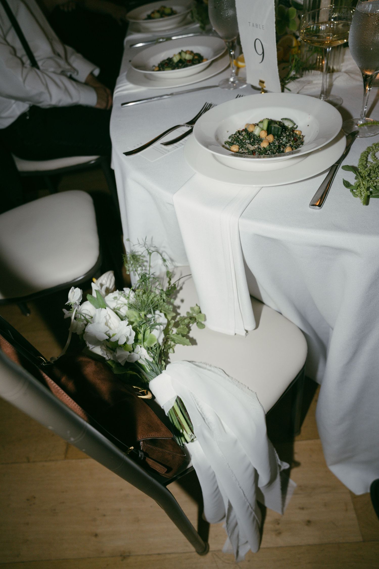 Wedding reception table details showing white linens, place settings and delicate floral arrangements.