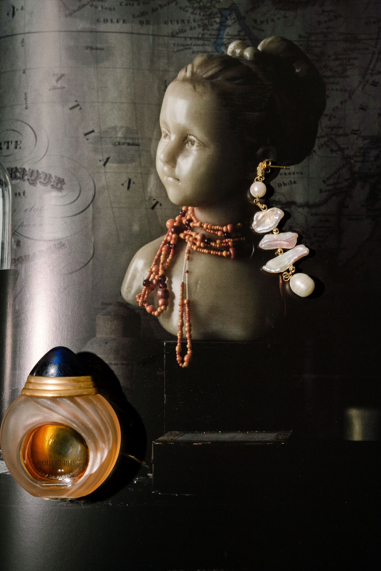 Artistic display of decorative dolls with beaded necklaces against a dark textured background.