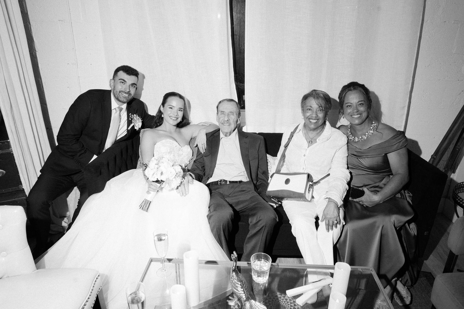 Wedding party group photo in black and white with bride groom and three guests seated together.