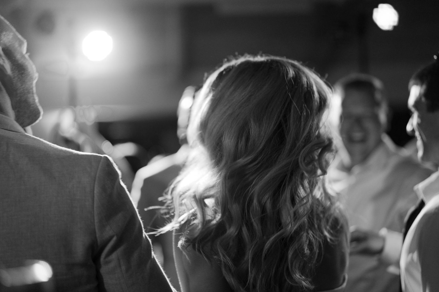 A backlit black and white photo capturing dancing silhouettes at an evening reception.