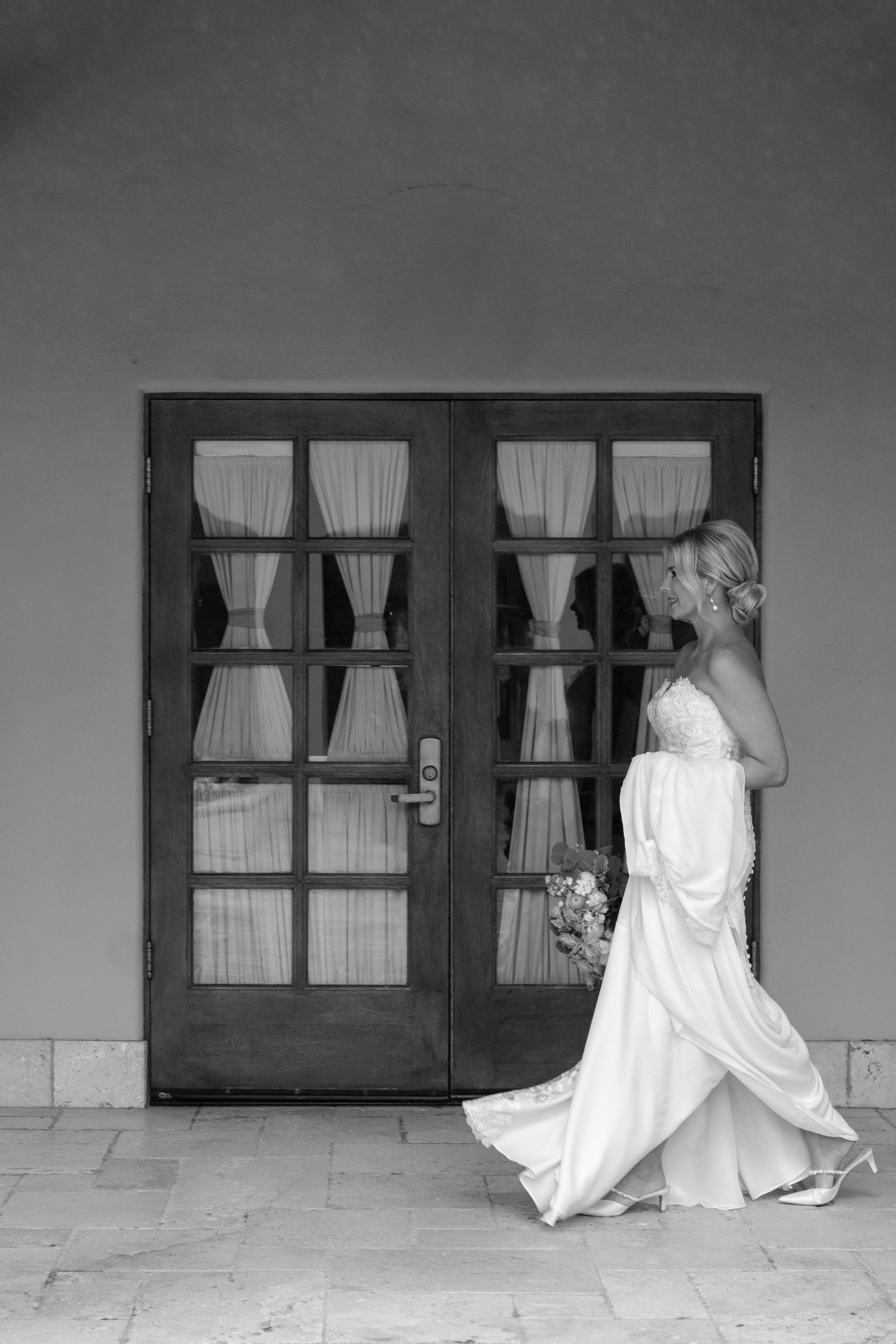Black and white sequence showing a bride's dress movement past windows in an architectural setting.