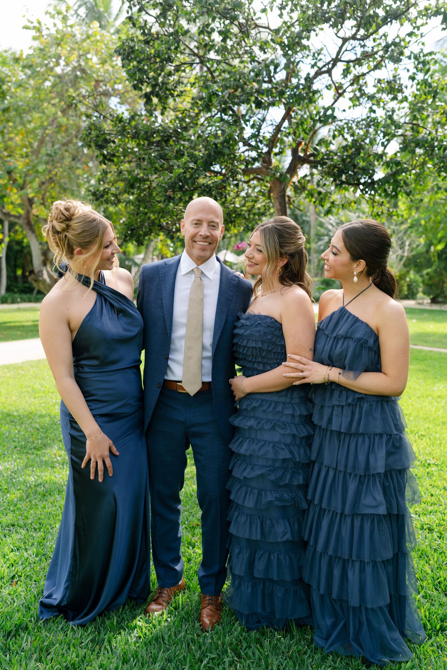 Wedding party in navy blue dresses posing outdoors on a sunny day.