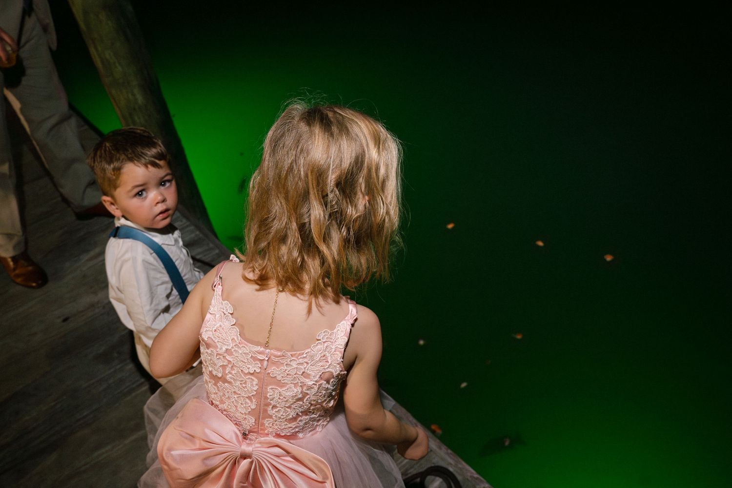 Wedding guests dancing and celebrating on a dance floor with green lighting effects.