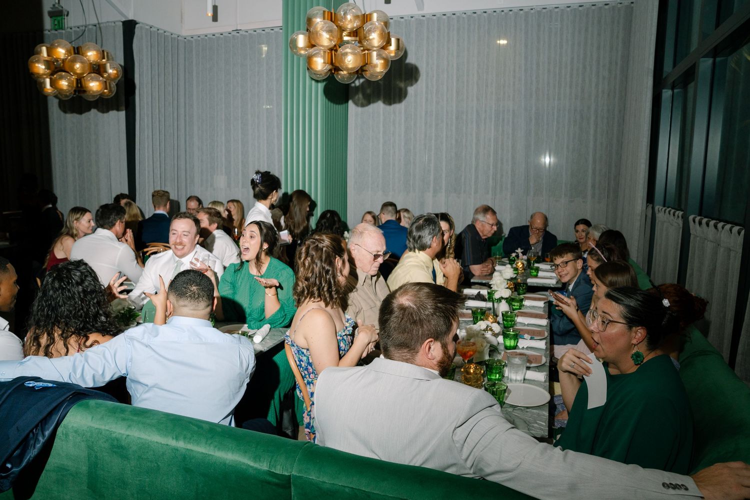 Large group gathered in an event space with green accents and modern decor for a special occasion.