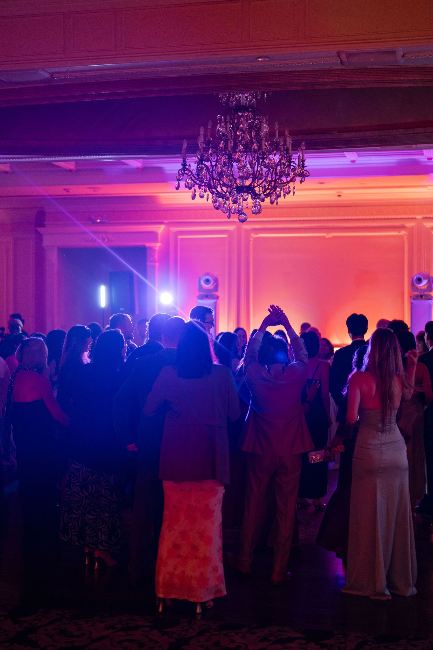 Wedding reception dance floor illuminated with dramatic purple and orange lighting.