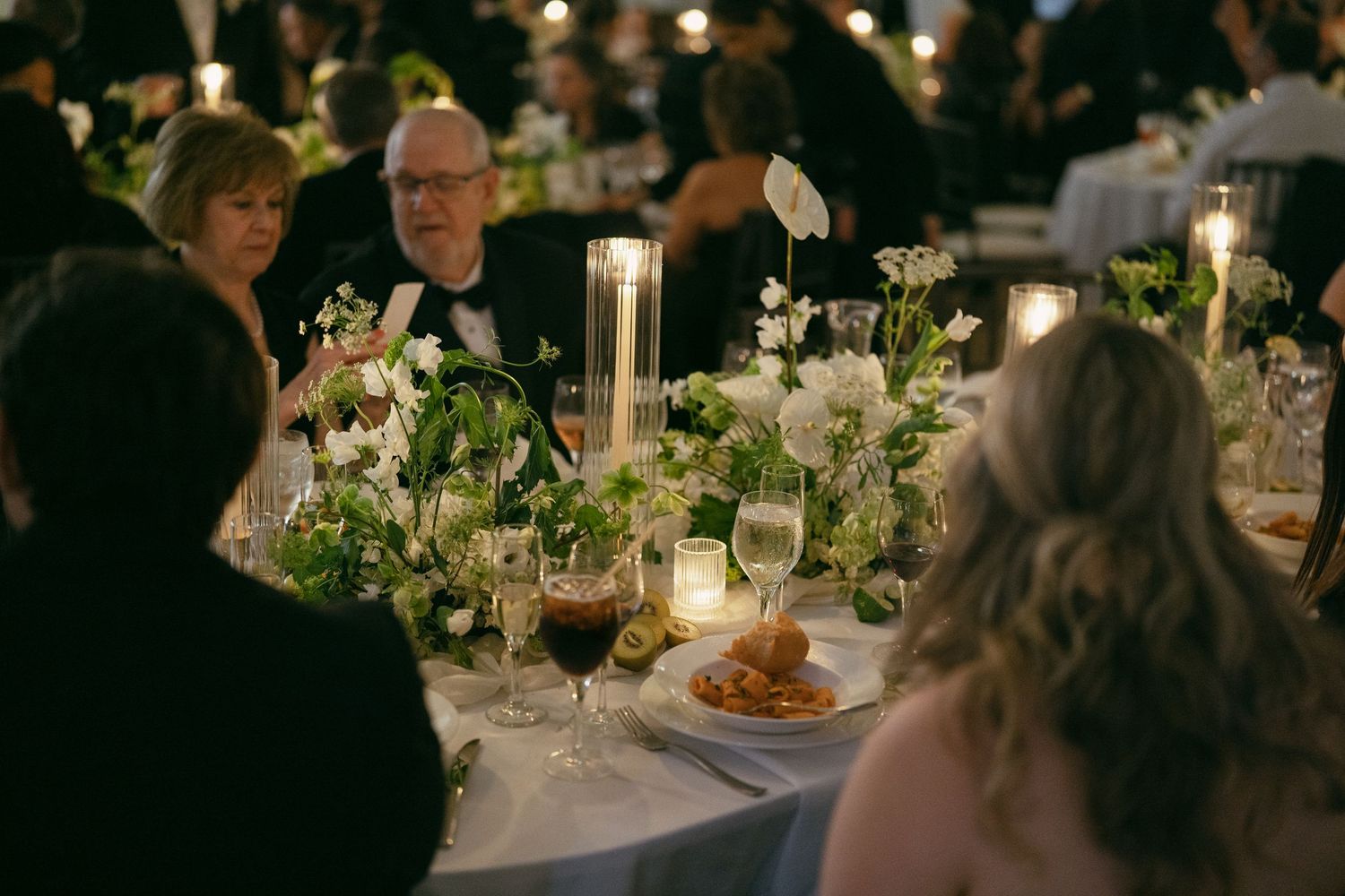 Elegant wedding reception table setting with candlelight and floral centerpieces.