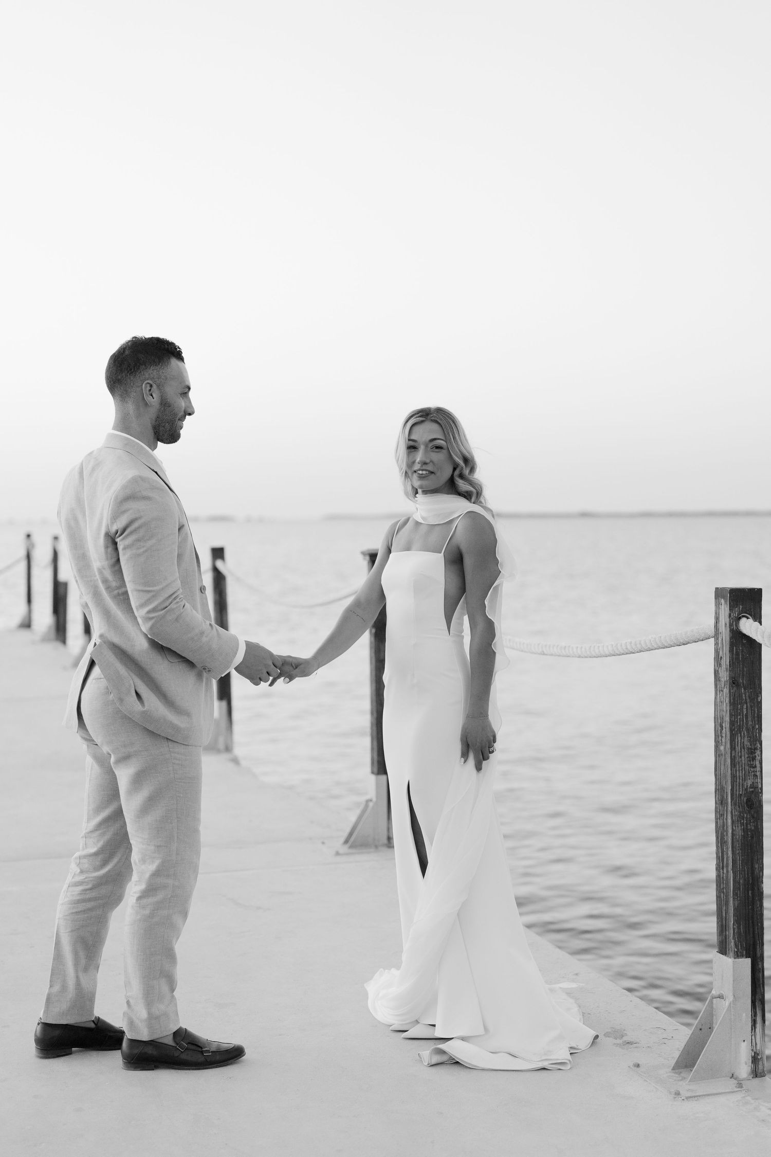 Black and white photos of a couple sharing intimate moments by the ocean.