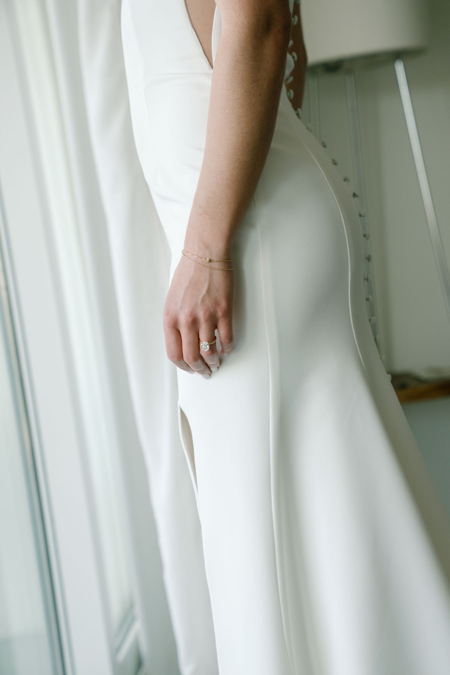 Close-up details of an elegant white wedding dress with delicate fabric and flowing design.