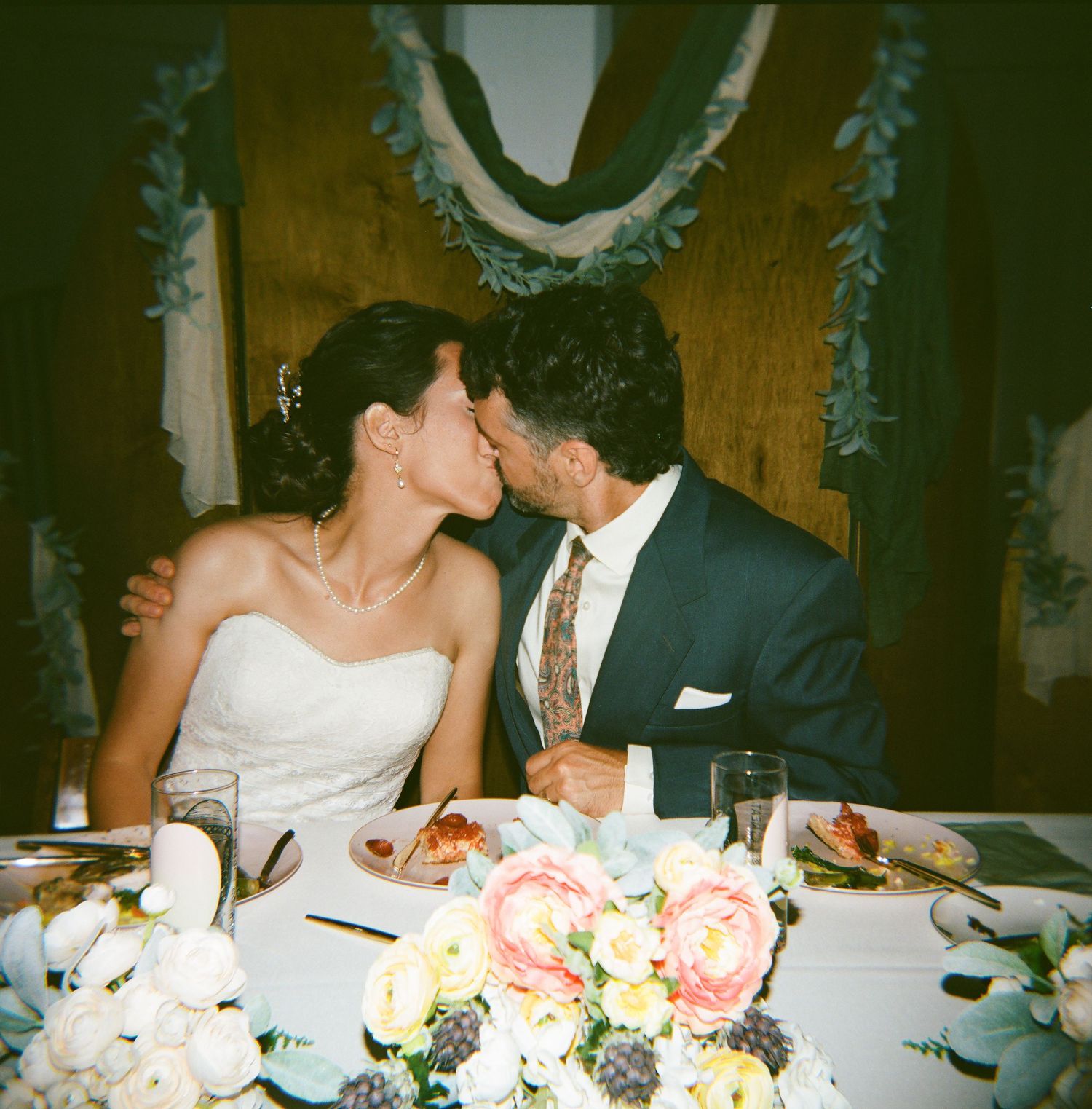 Candlelit wedding reception dinner with floral centerpieces and place settings.