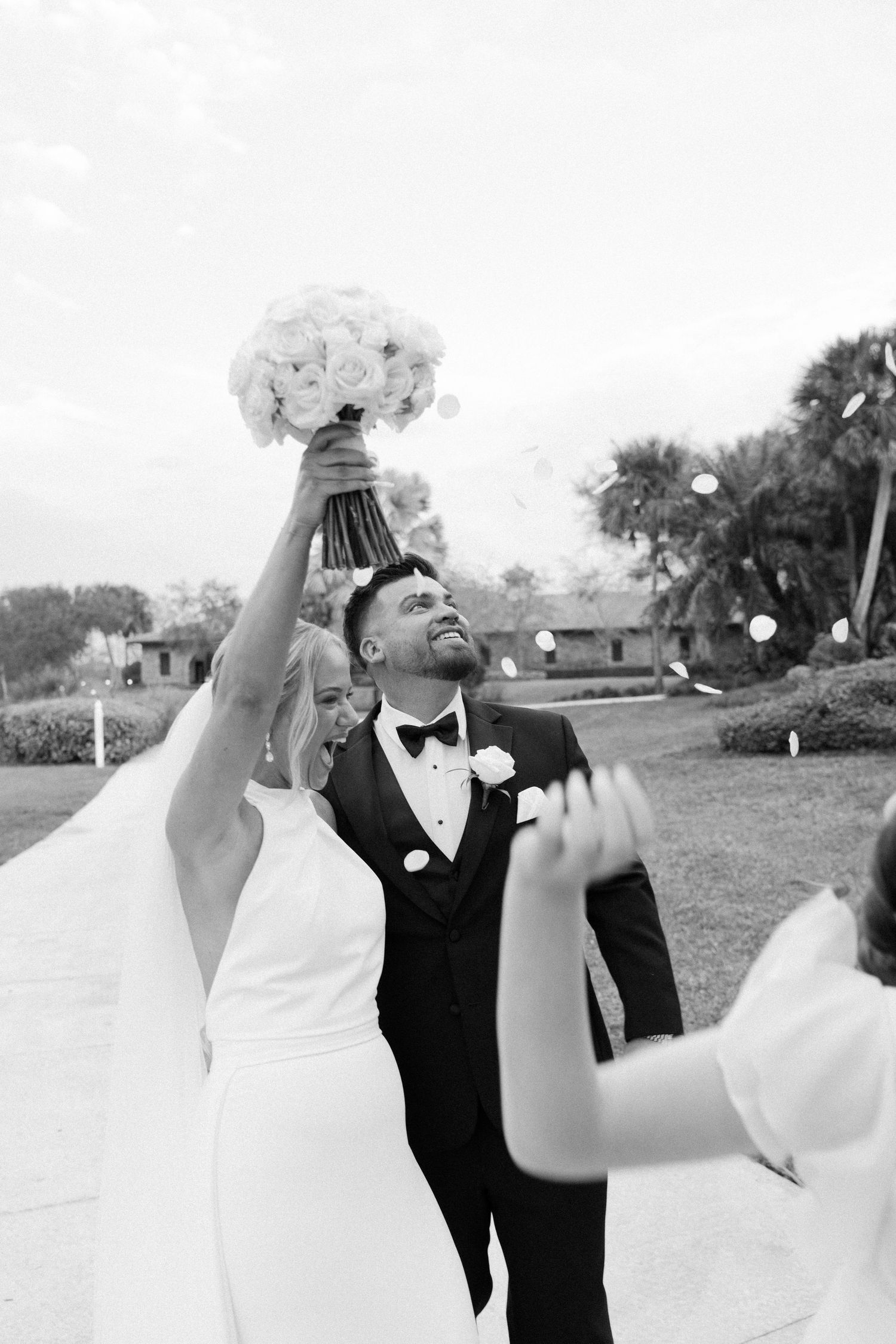 Wedding couple dancing outdoors in joyful celebration with white dress and dark suit.