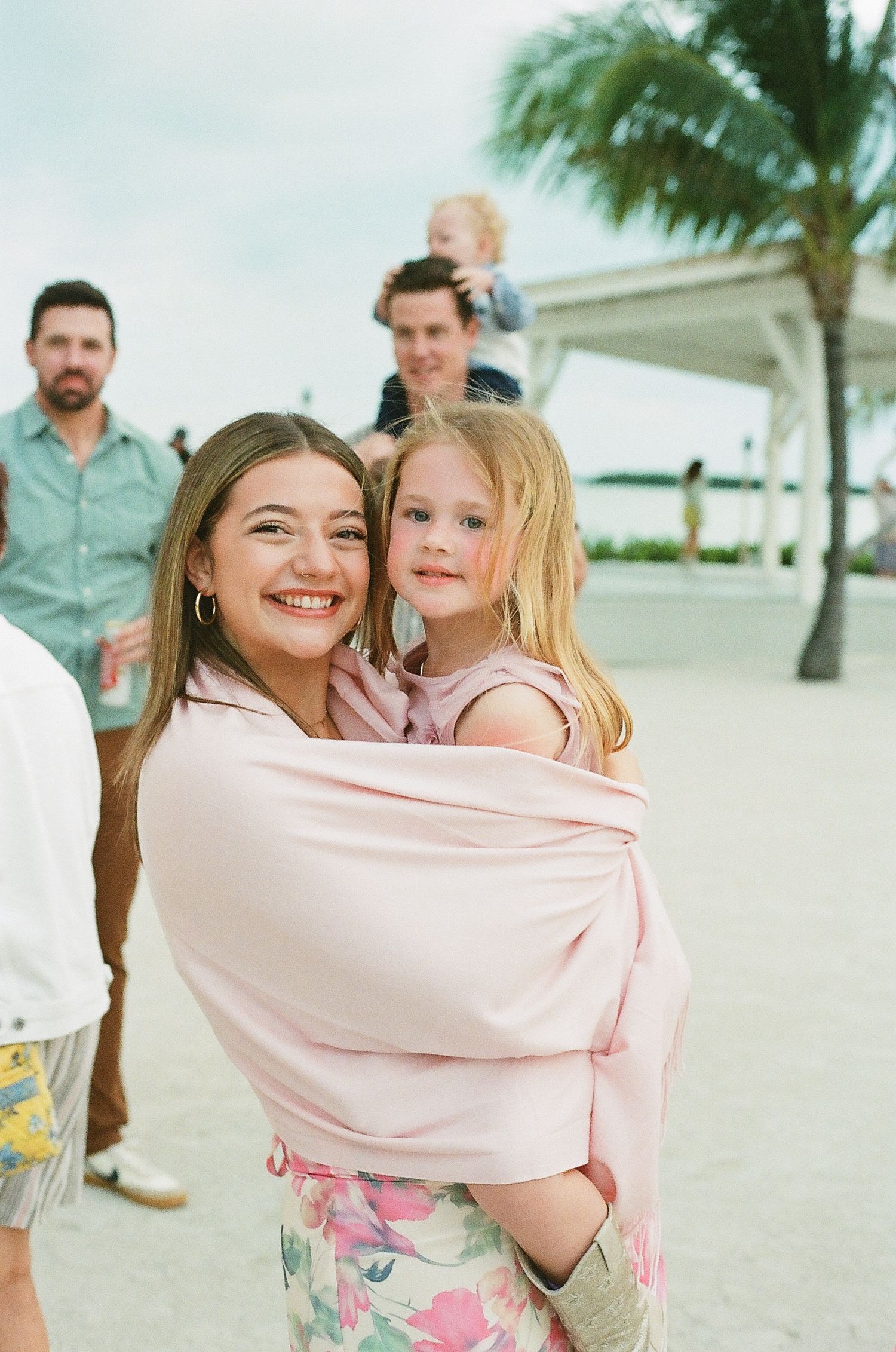 A beachside family gathering with palm trees and a gazebo in the tropical background.