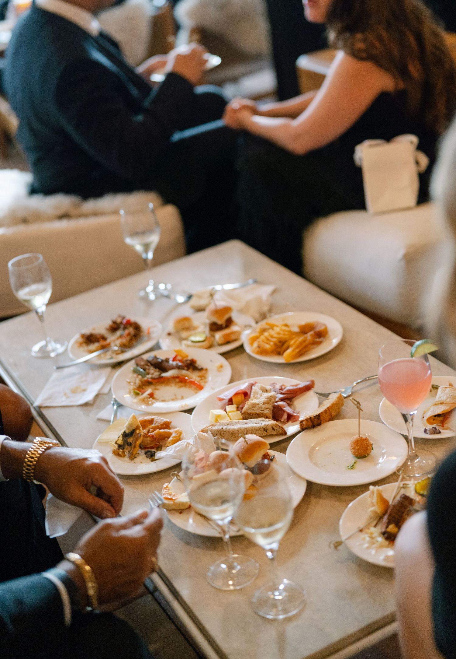 Elegant wedding reception dinner plates with gourmet food and wine glasses on white tablecloths.
