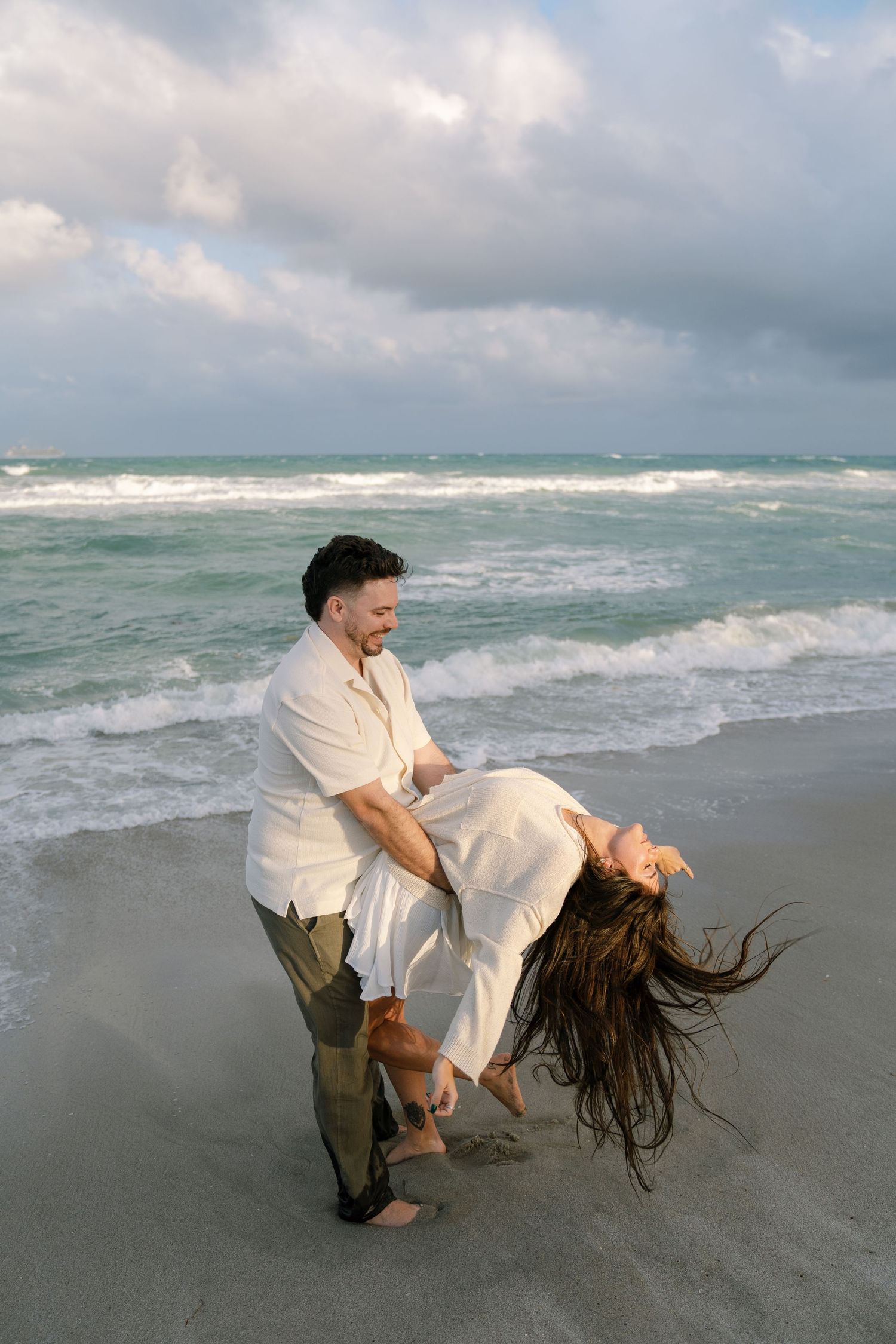 A sequence of photos showing a person flipping their wet hair on a stormy beach with crashing waves in the background.