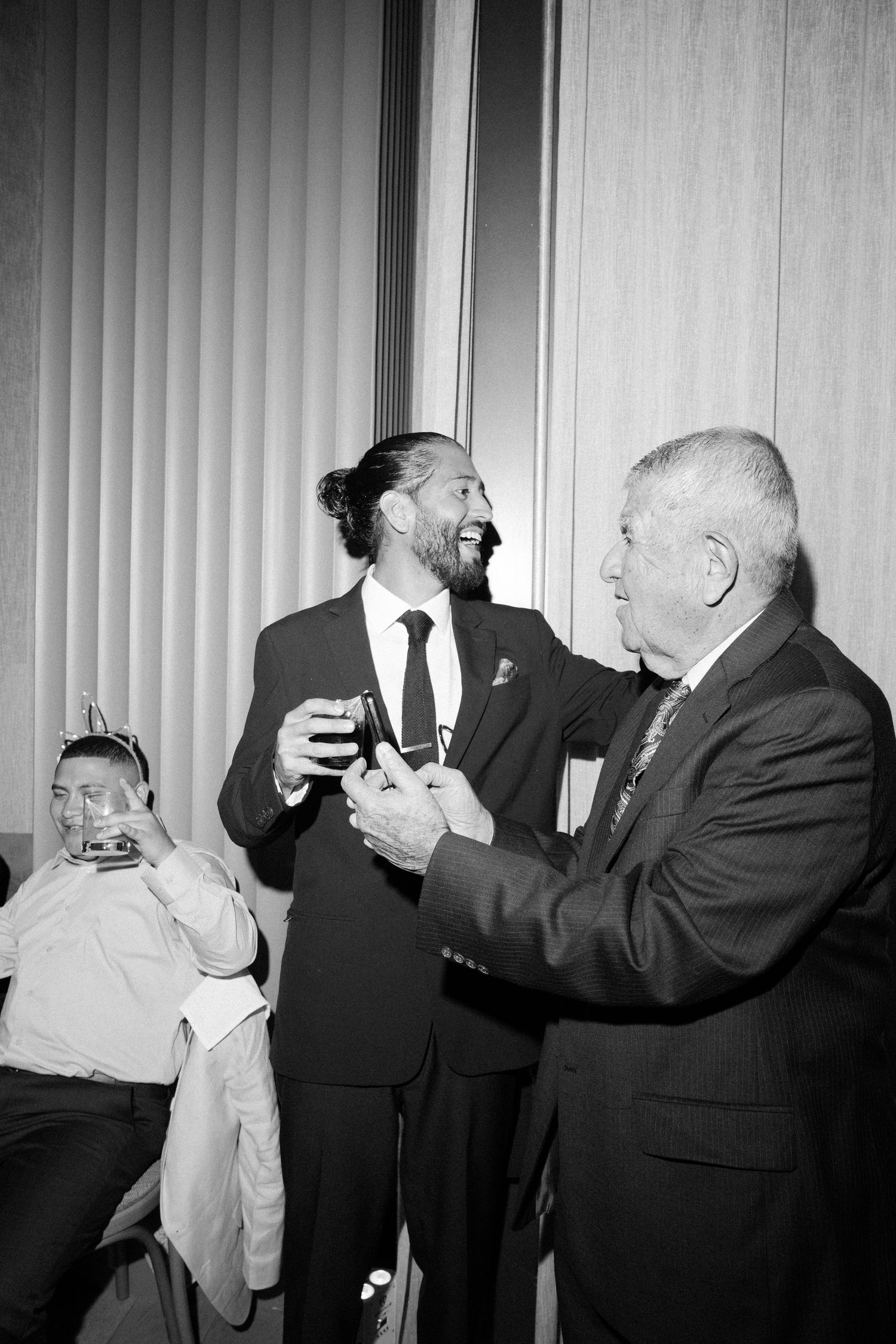 Black and white sequence showing men in suits raising glasses in a toast at a formal gathering.