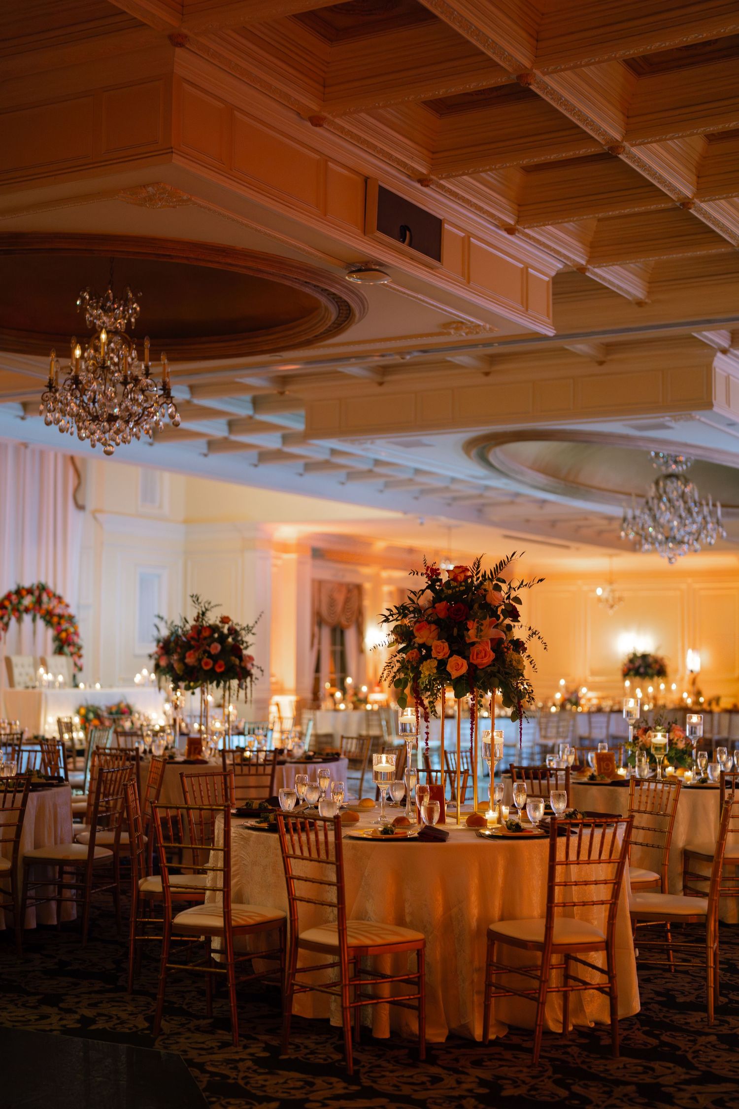 Elegant ballroom wedding reception with crystal chandeliers and floral centerpieces.