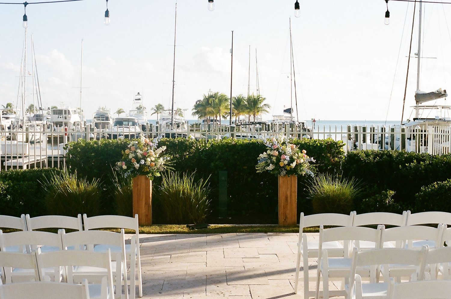 Outdoor waterfront wedding venue with white chairs and marina views.