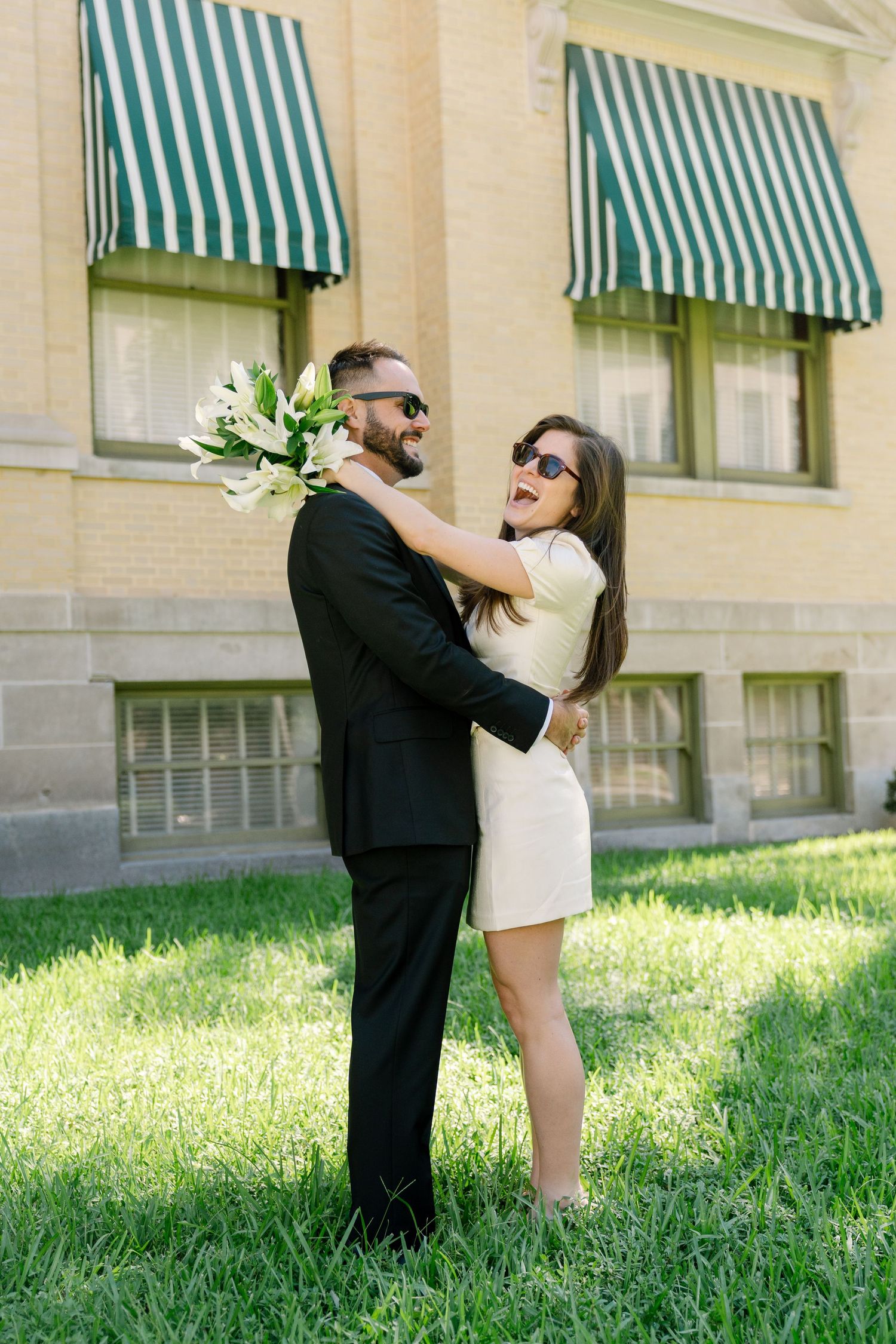 Series of romantic dance poses between two people on a grassy lawn with striped awnings in background.