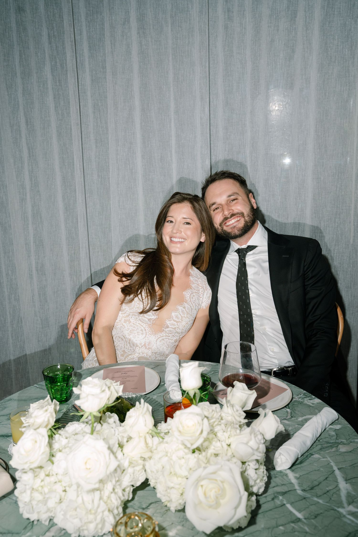 Candid reception moments with white floral centerpieces on a gray tablecloth.