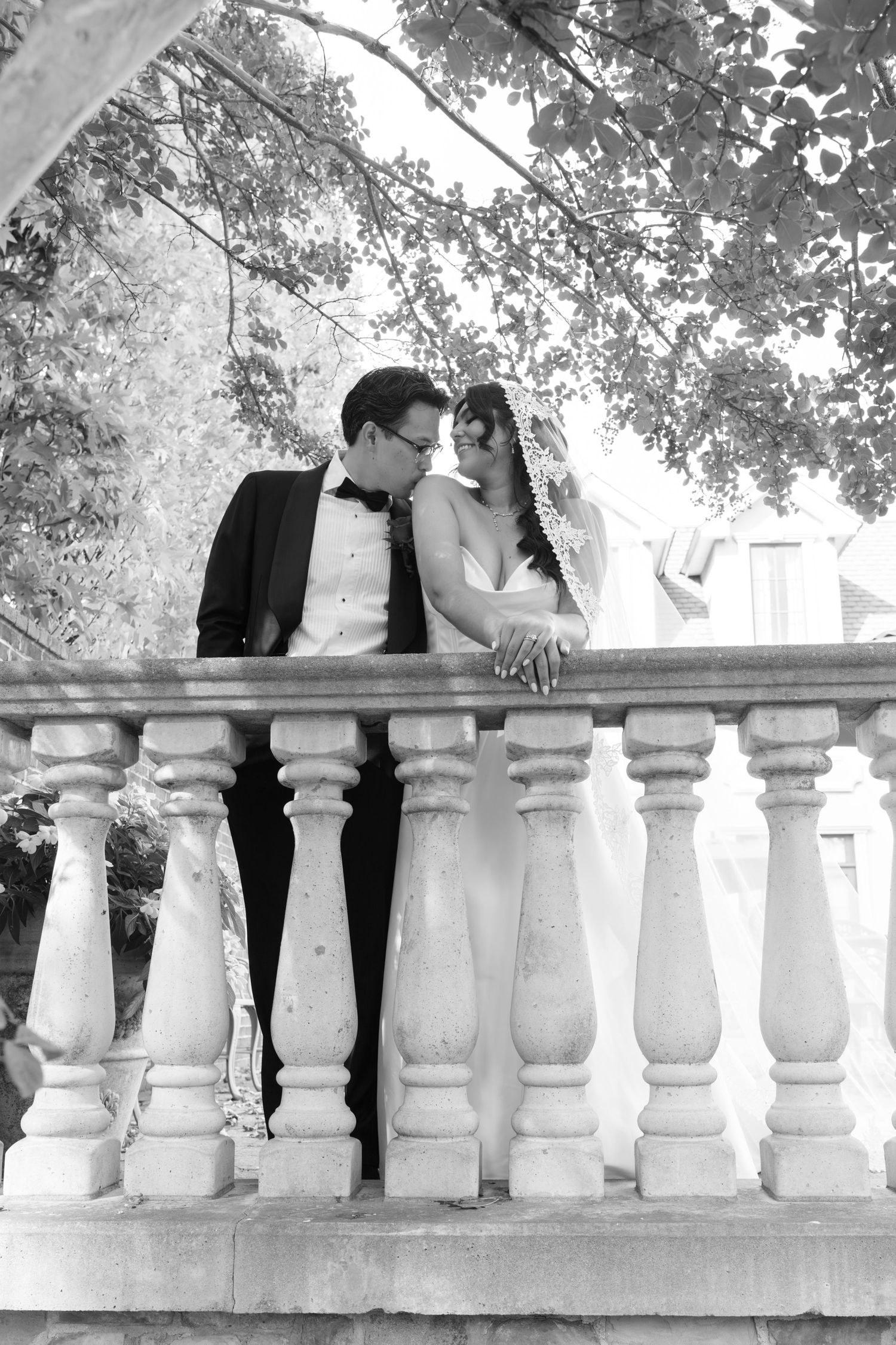 Black and white wedding photo series showing couple behind ornate stone balustrade railing.