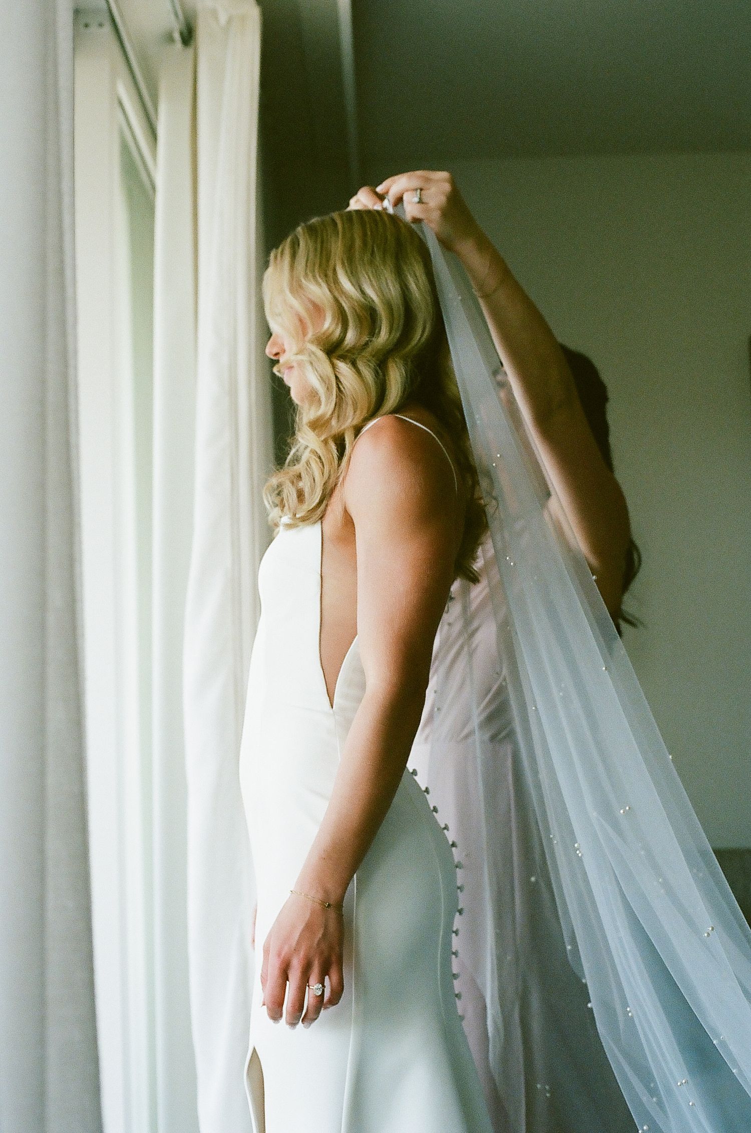 A flowing white wedding veil hangs elegantly against a light-colored wall.