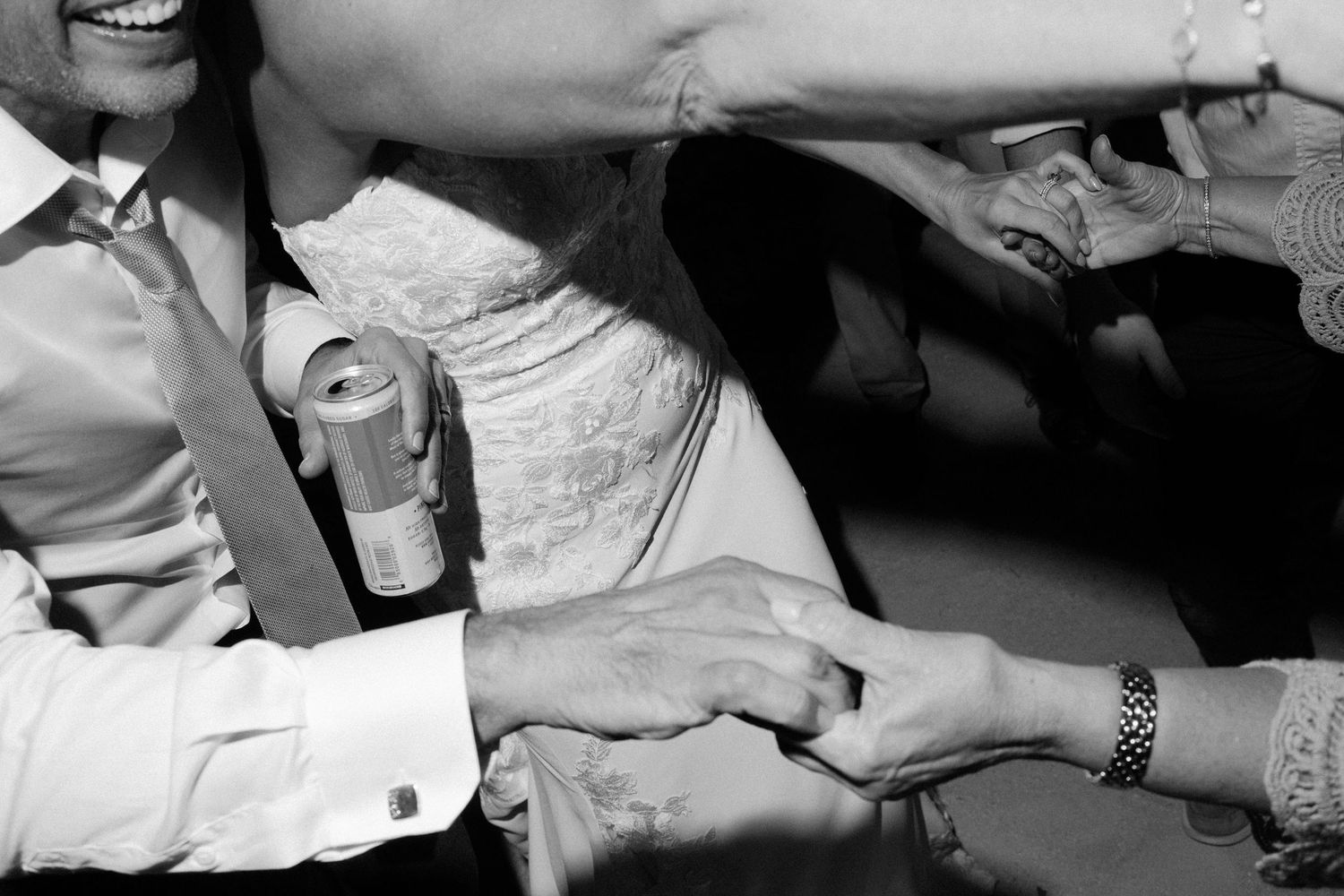 Black and white close-up of hands during a wedding celebration.