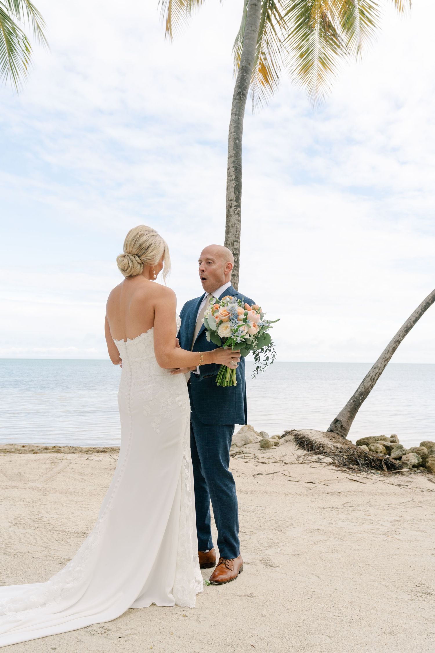 Wedding couple sharing an intimate moment on a tropical beach with palm trees.