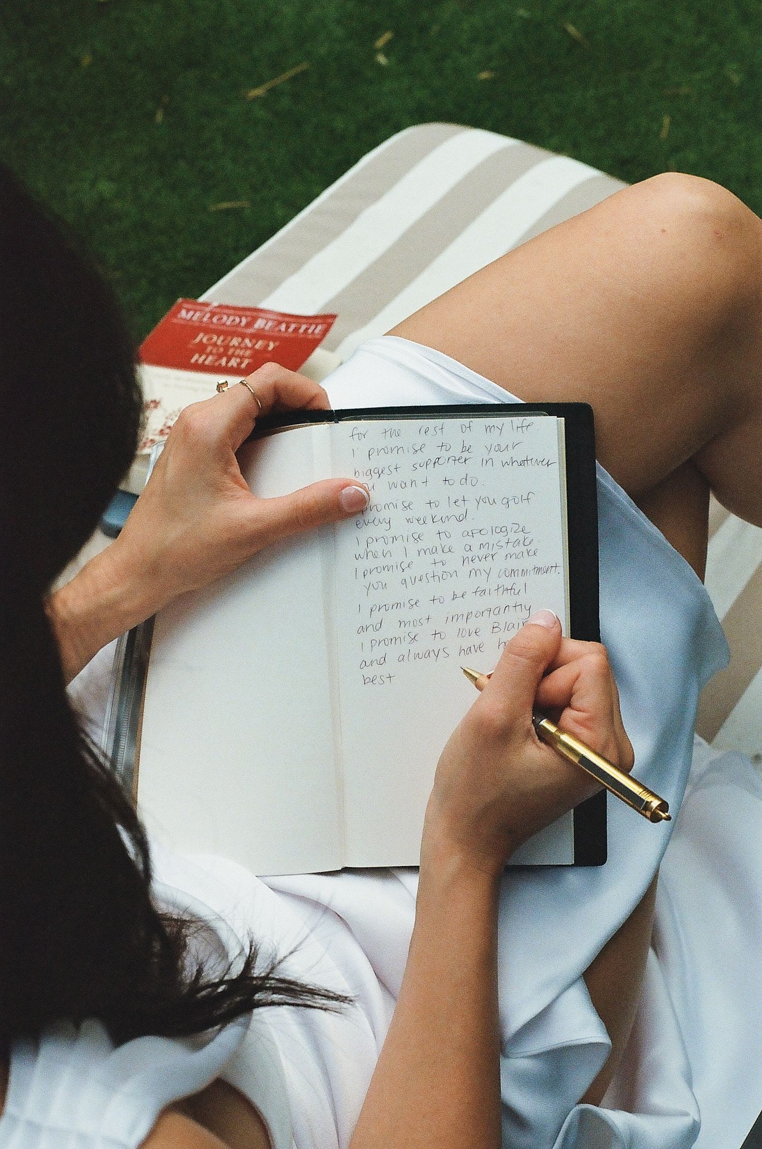 Close-up shots of hands writing in a notebook outdoors on a sunny day with green foliage in the background.