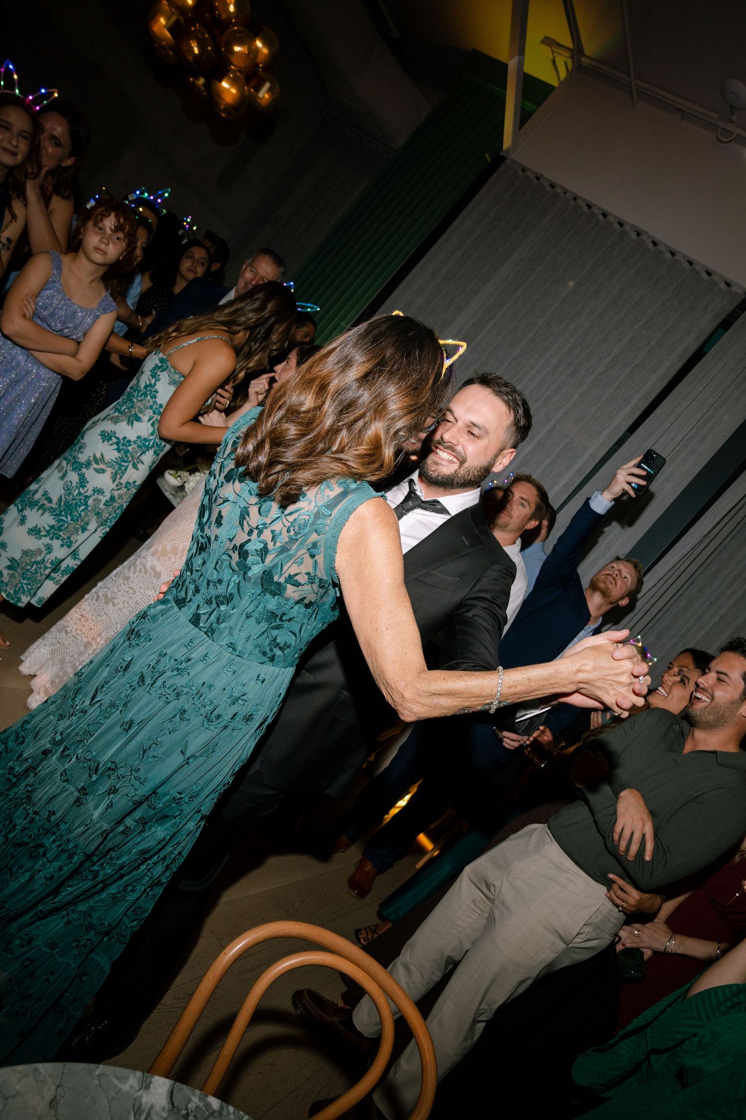 Couples dancing and celebrating at evening wedding reception with teal decor.