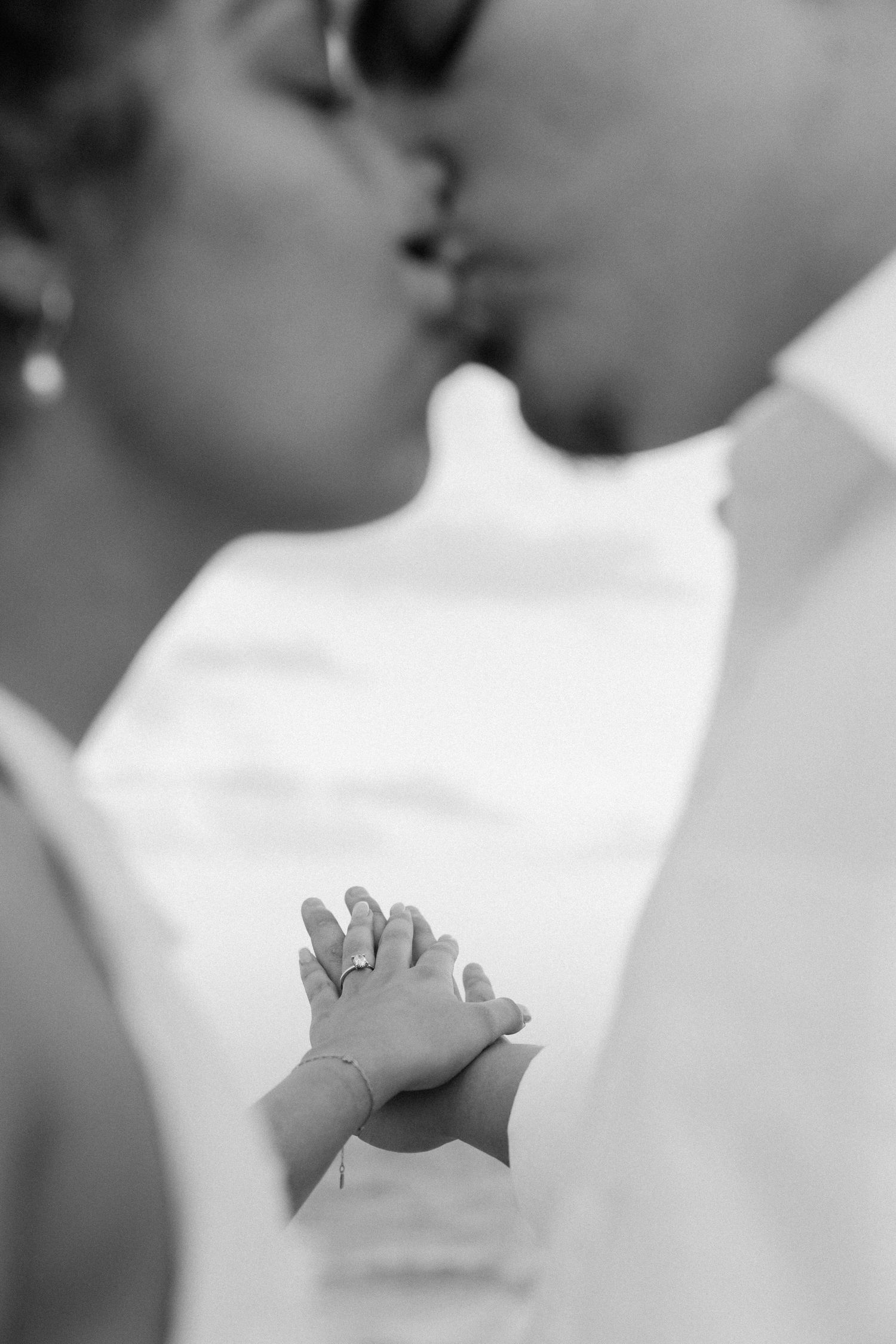 Black and white photo showing hands clasped together in prayer or unity against a light background.