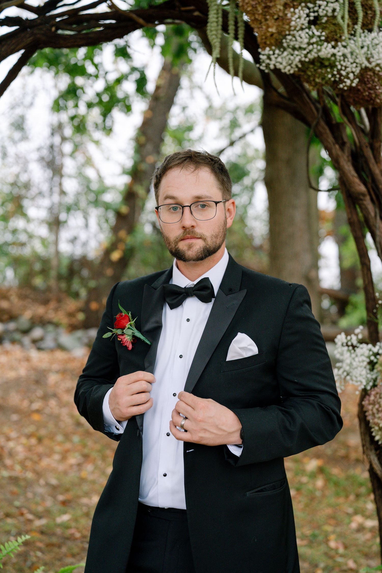 A formal event preparation showing details of a black tuxedo and red boutonniere.